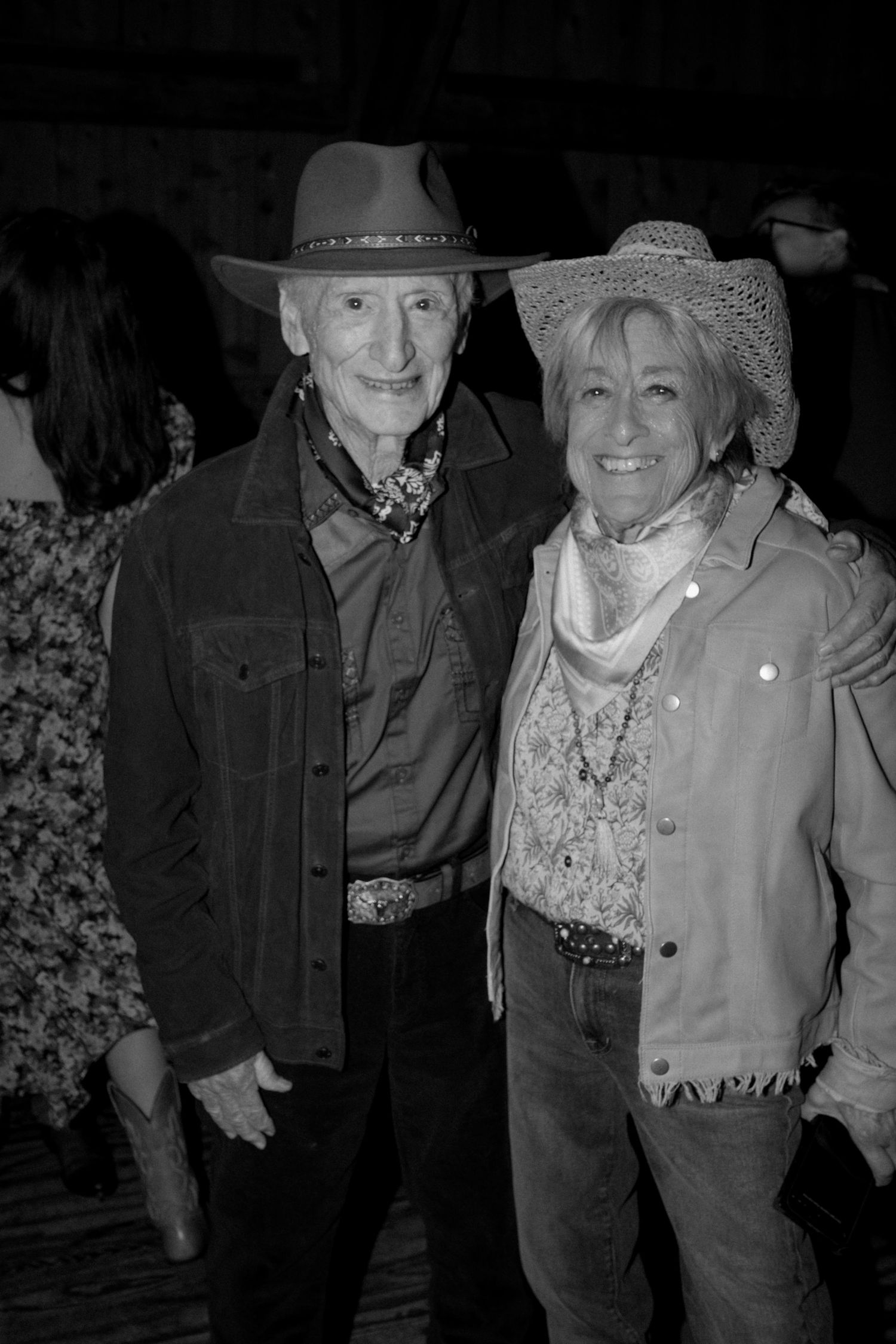 Western-styled couple in cowboy hats at evening event.