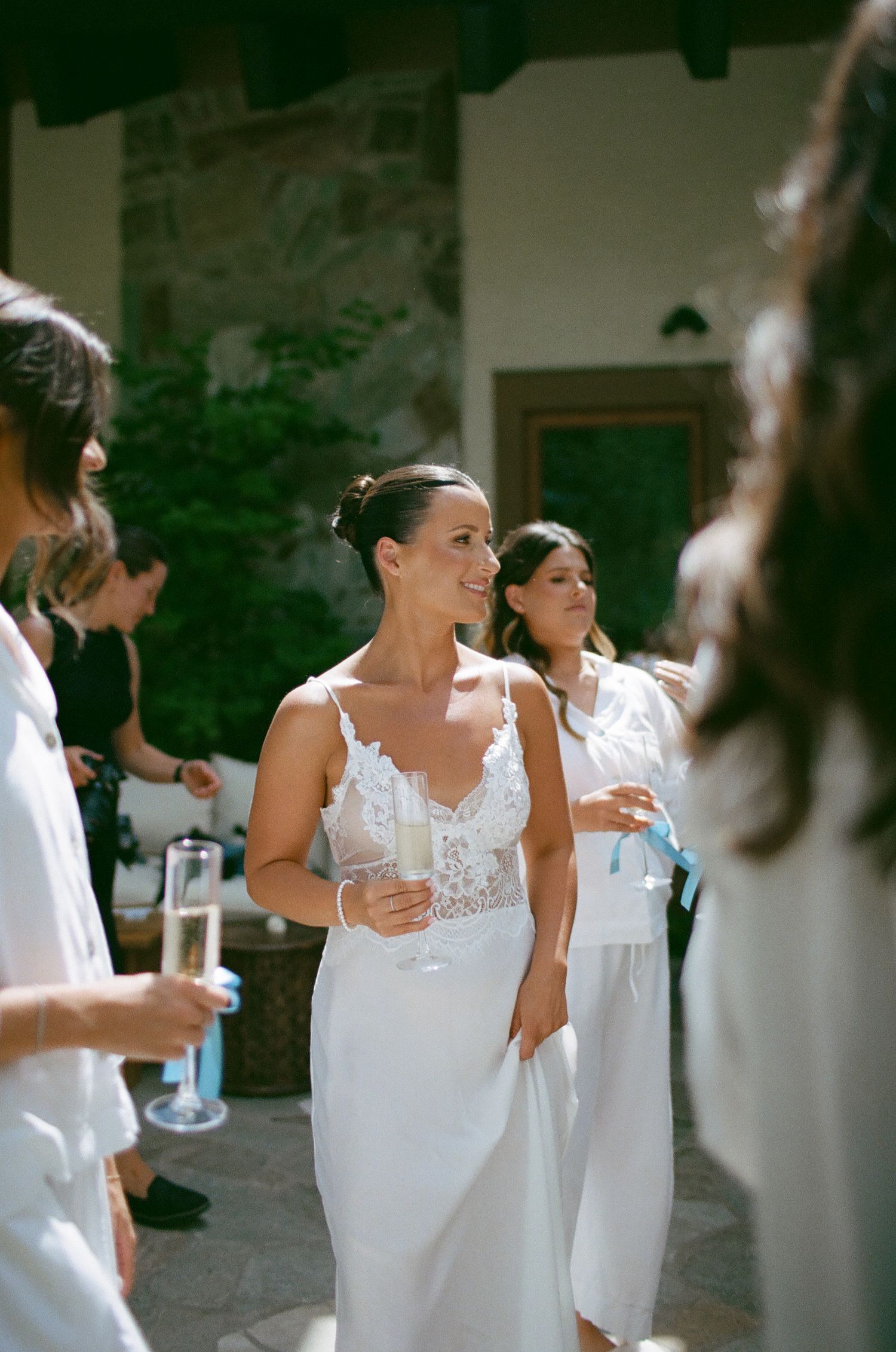 Wedding party members in white dresses gather during an outdoor celebration.