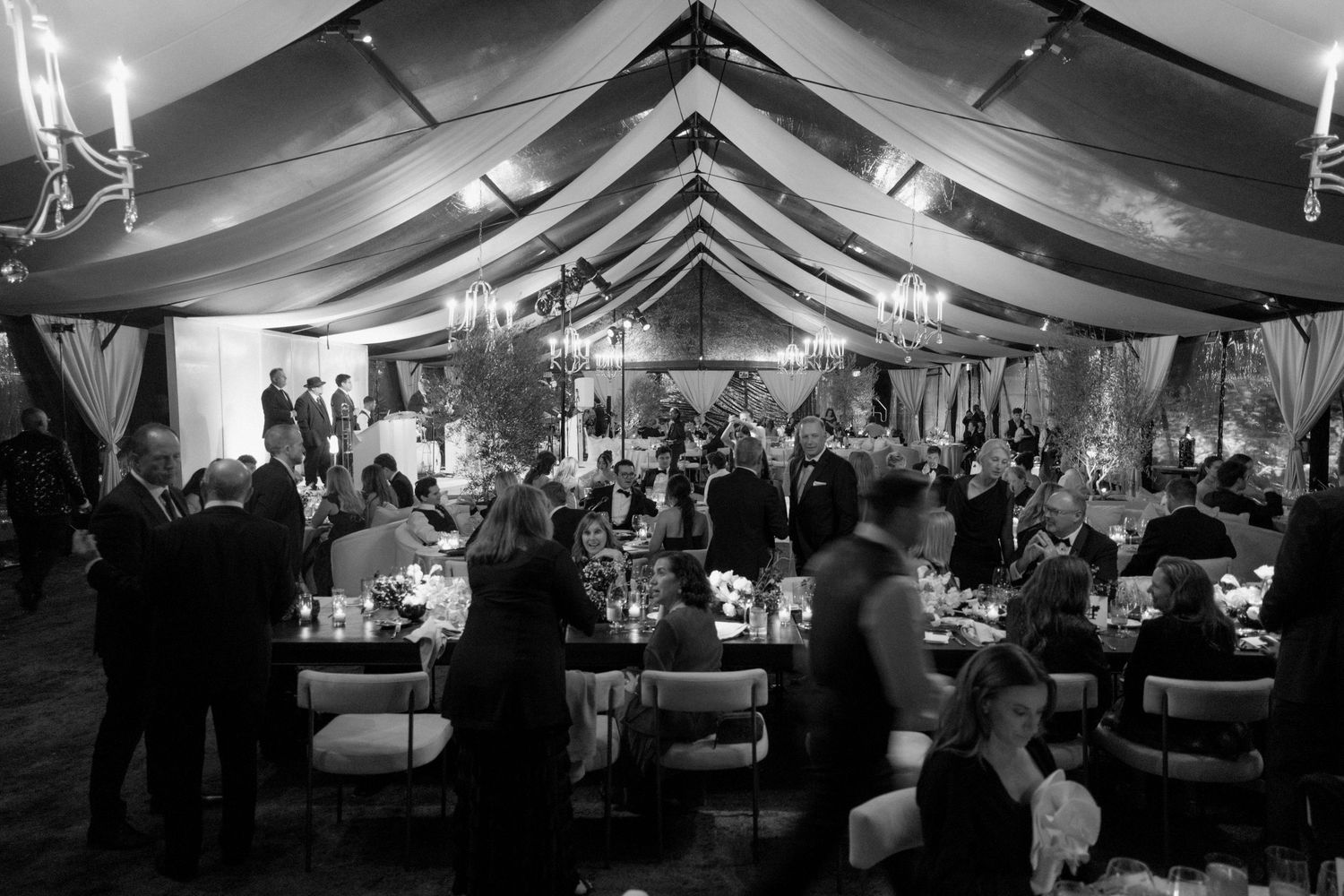 Panoramic view of an elegant wedding reception tent with dramatic lighting and draped fabric decor.
