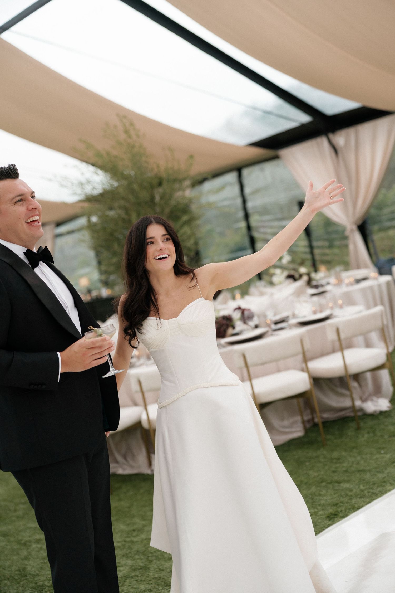 A couple dances under an elegant outdoor tent during their wedding reception.