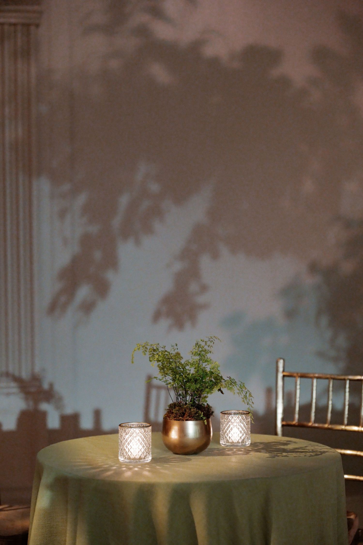 A table with decorative items and greenery set against a blurred natural backdrop.