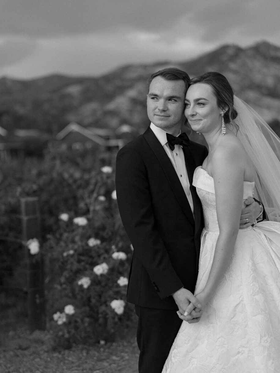 A romantic black and white portrait of newlyweds against a mountain landscape.