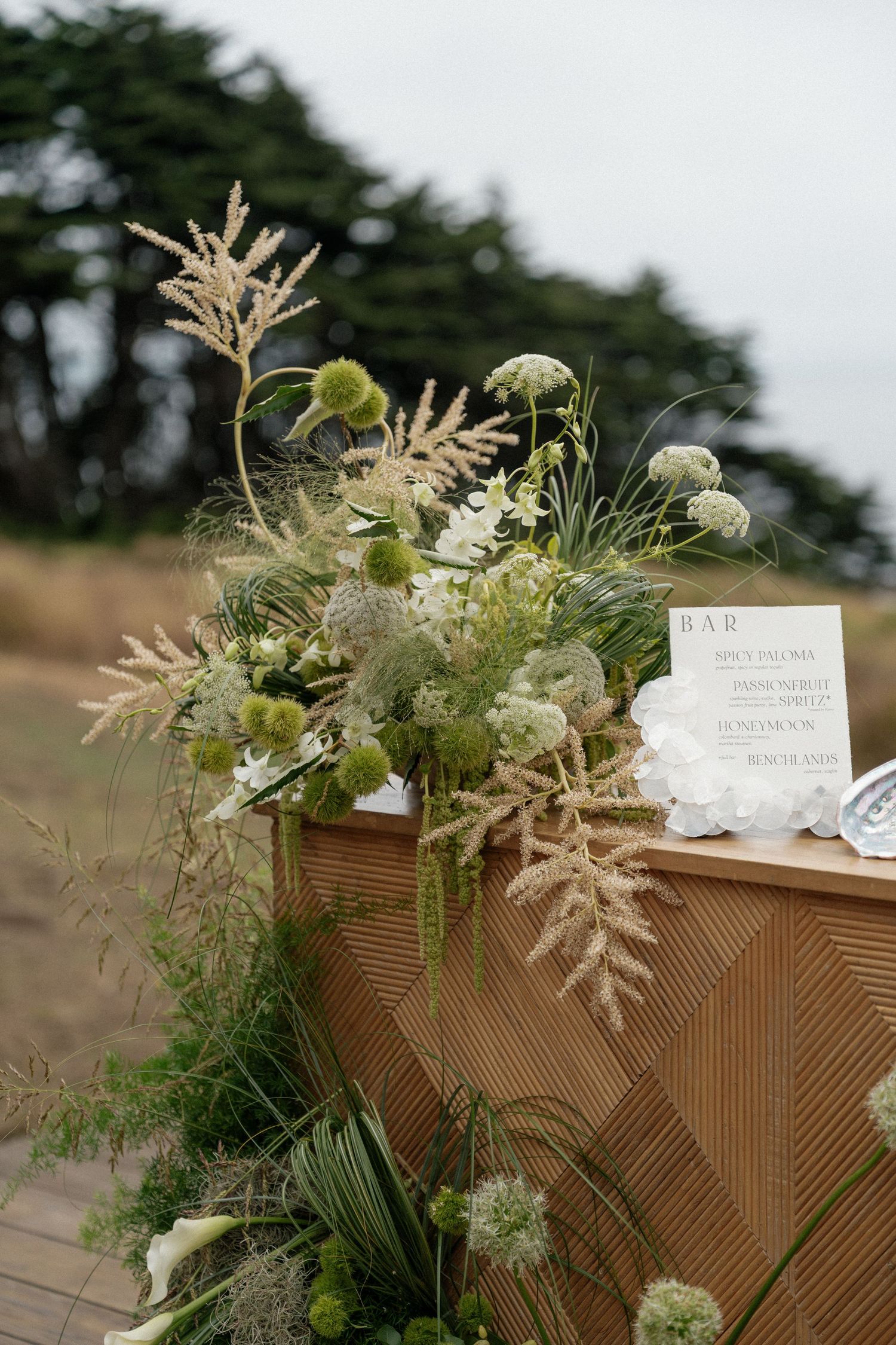 Rustic wooden table decorated with dried pampas grass and white floral arrangements.