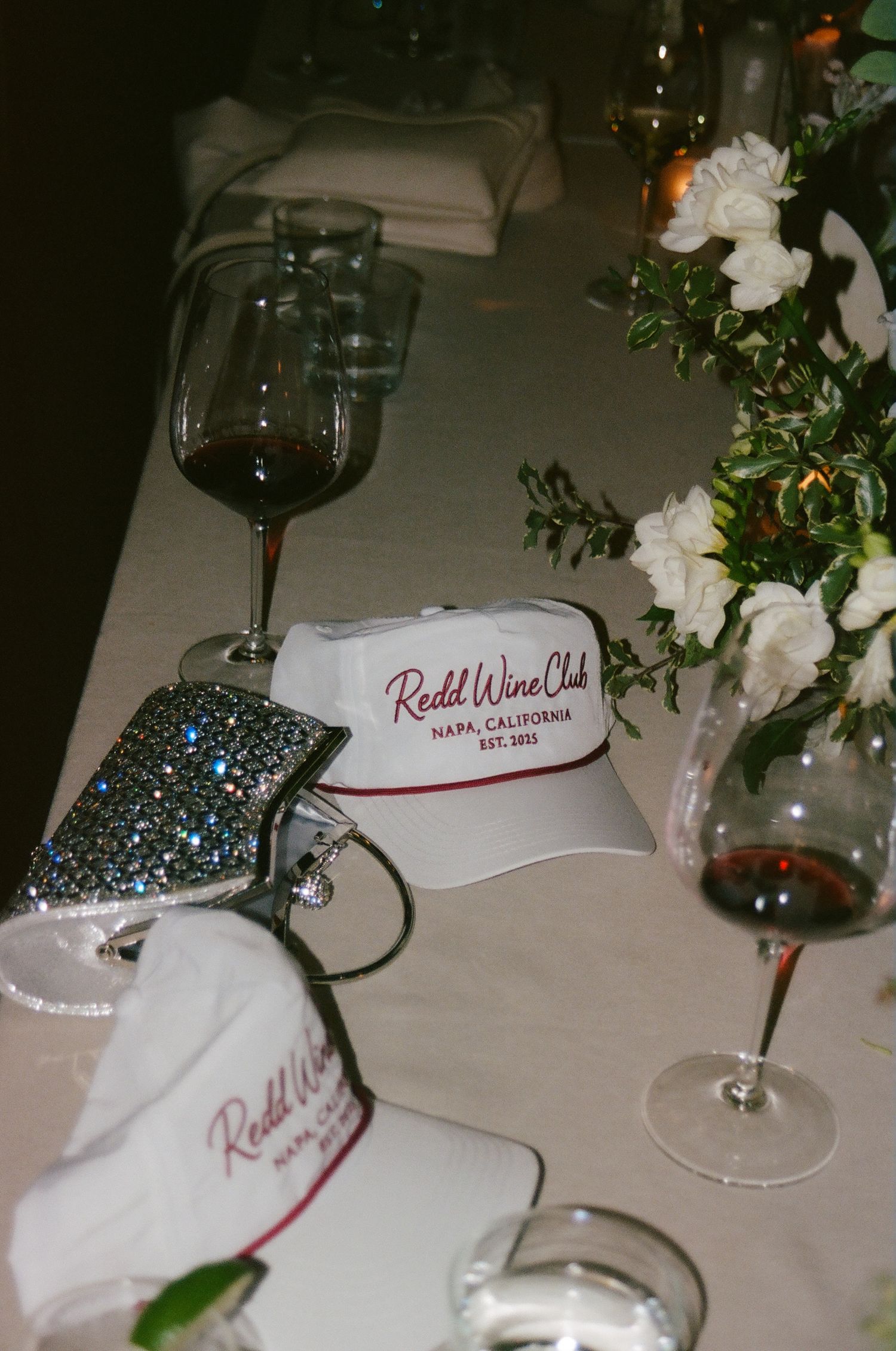 Elegant table settings at a wedding reception with wine glasses and white floral arrangements.