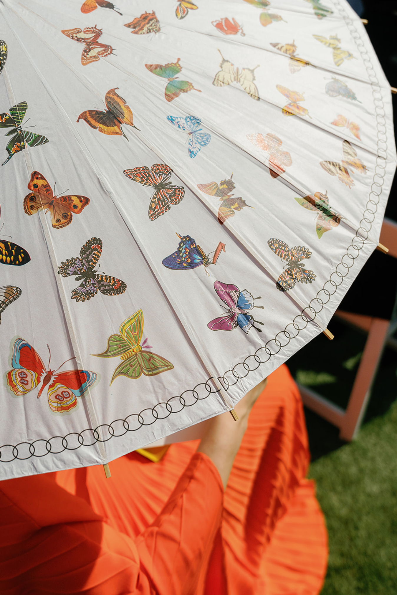 White decorative parasol with colorful butterfly patterns against an orange background.