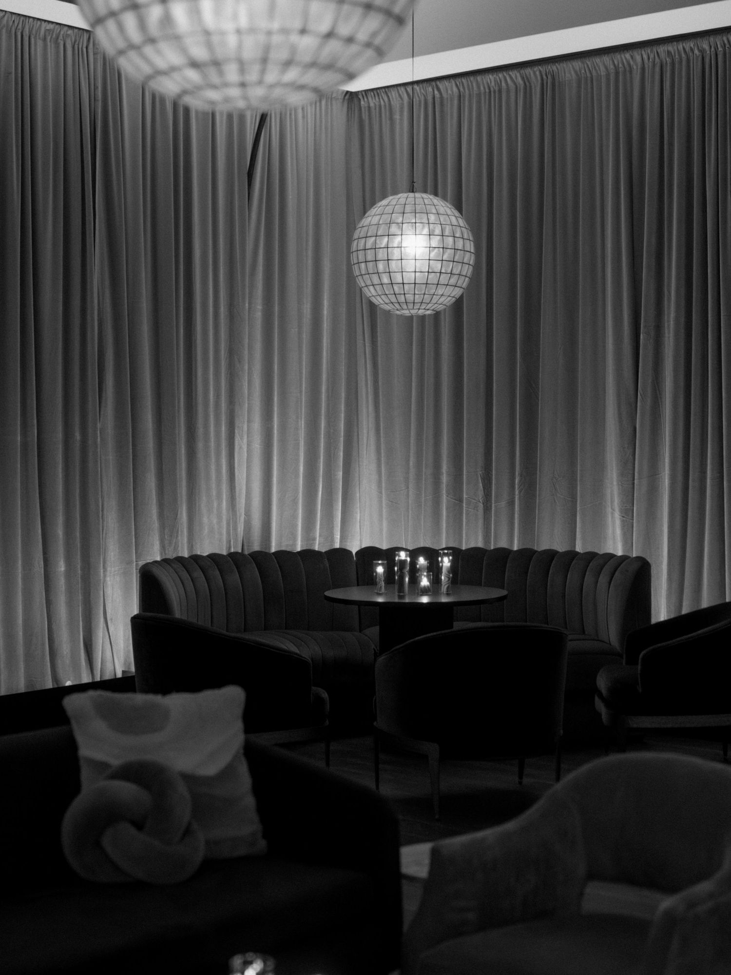 Modern lounge area with dramatic lighting and draped curtains featuring a disco ball ceiling fixture.