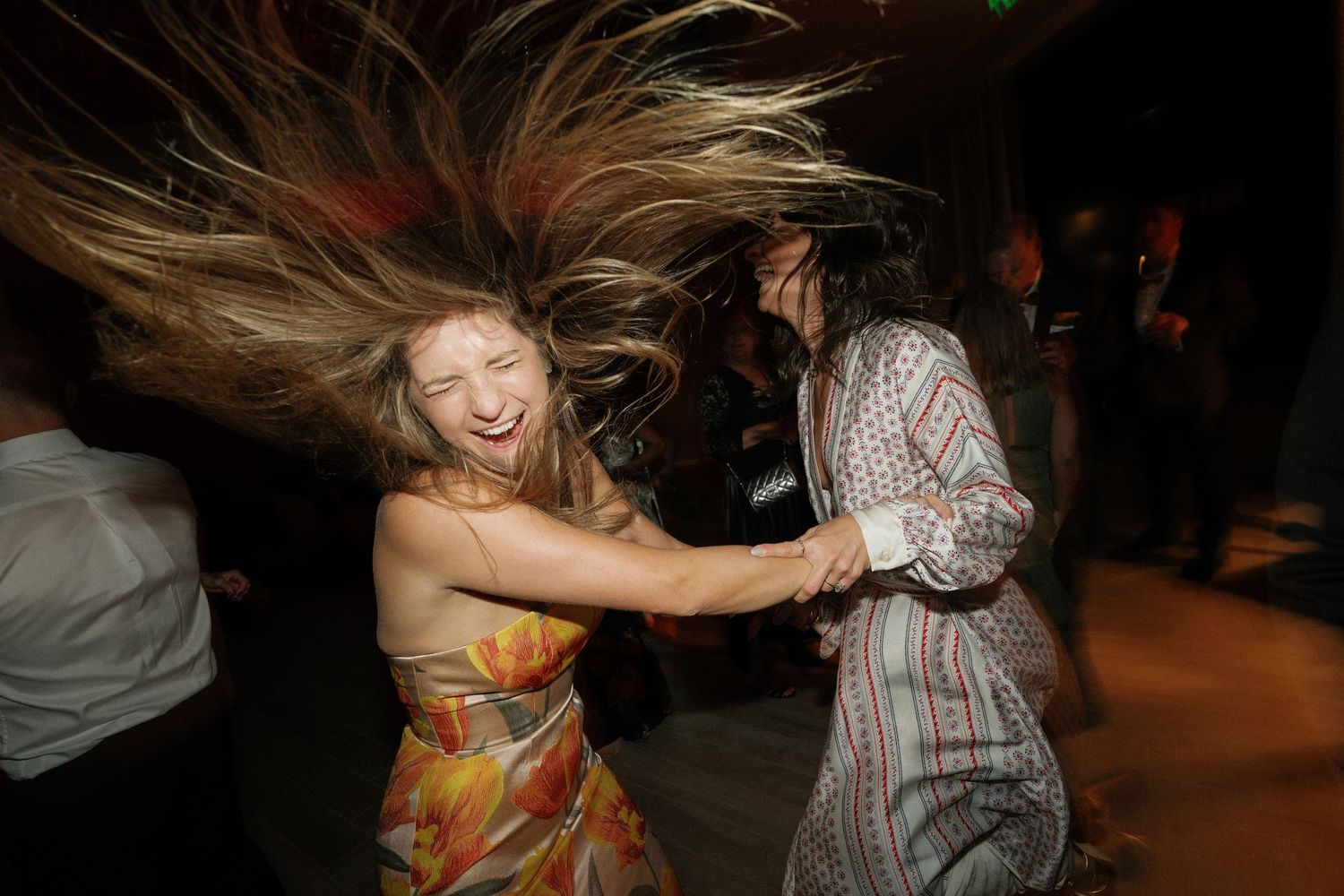 A couple dancing together at a wedding reception in a dimly lit venue.