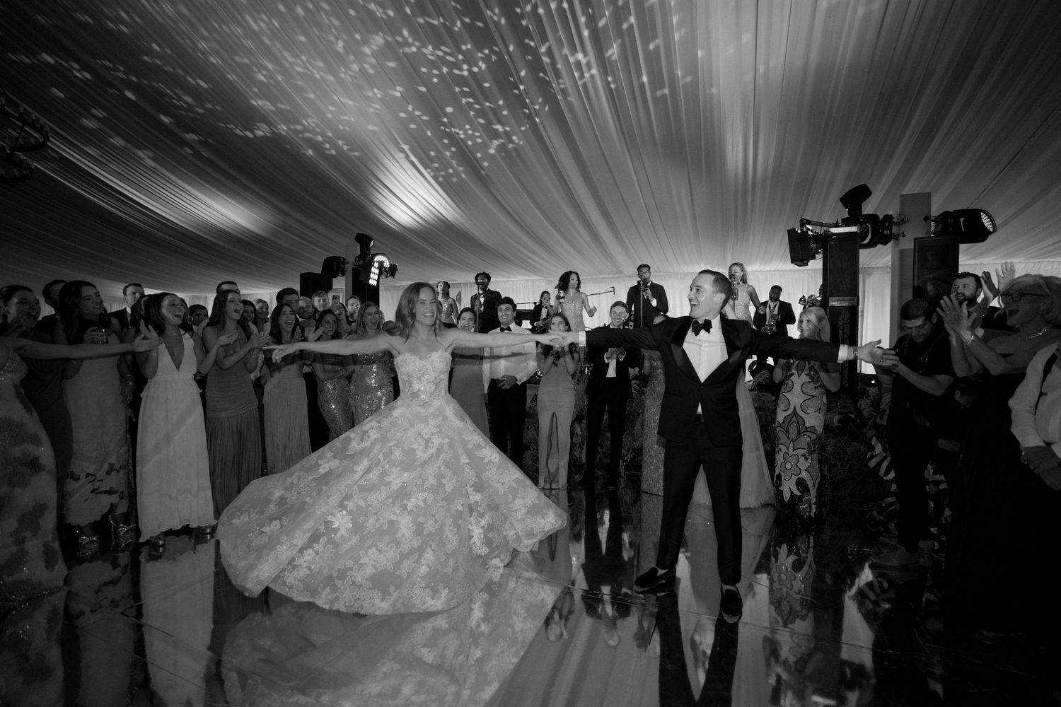 Black and white photo capturing the ambiance of a wedding reception under a tent.