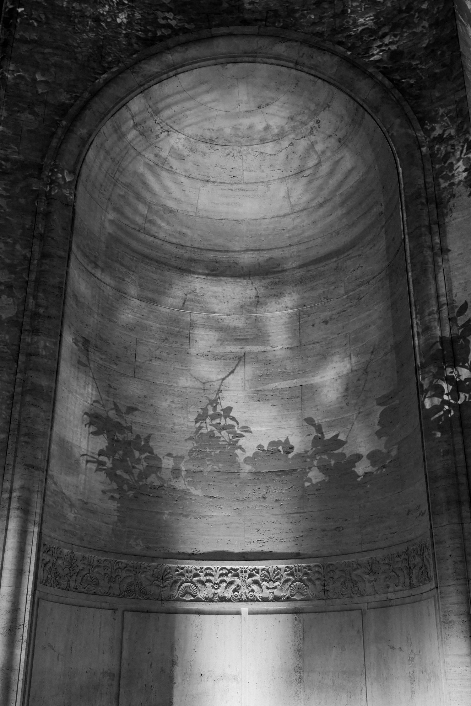 A black and white image showing an arched architectural structure with intricate designs.
