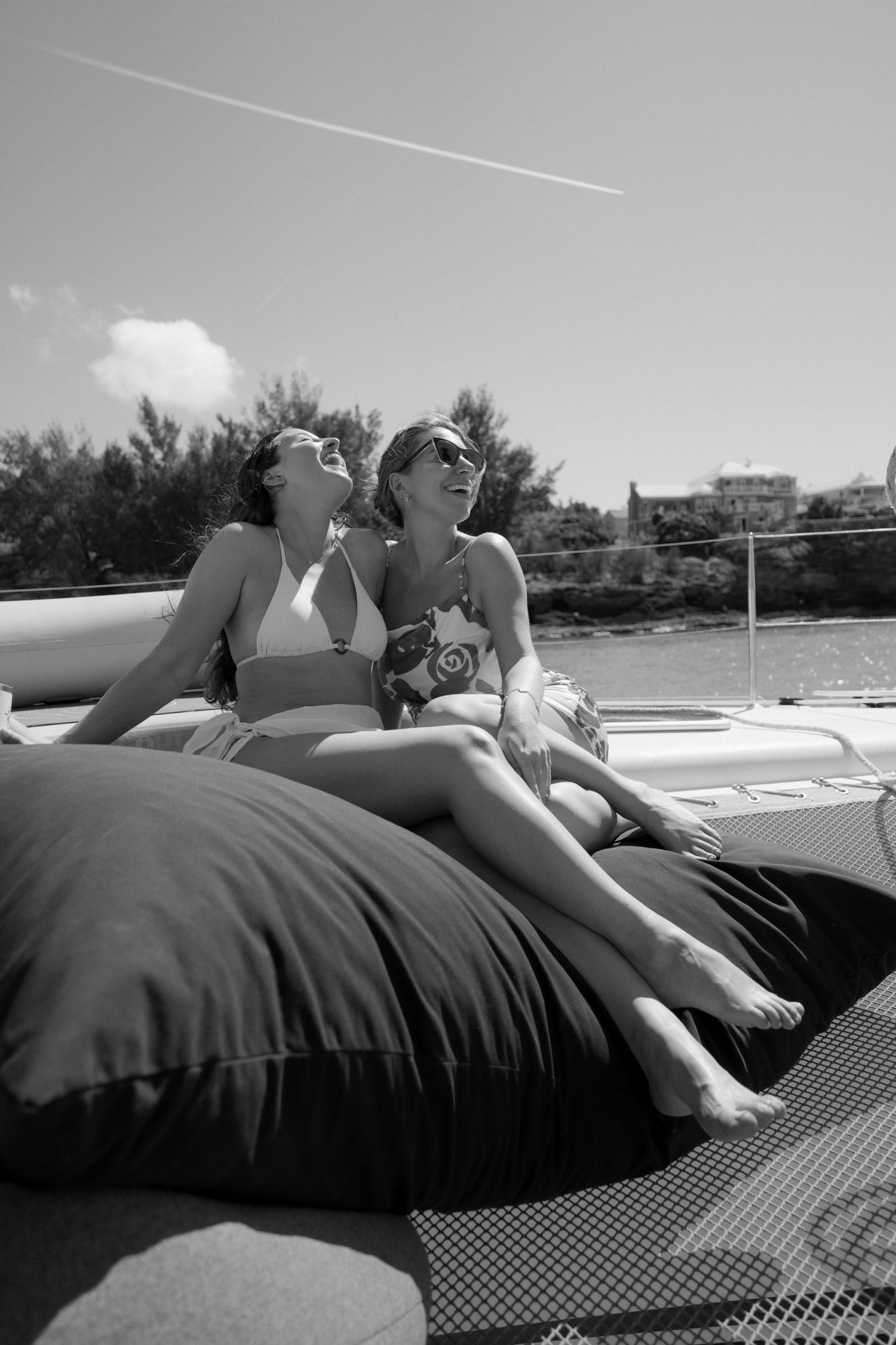Two women relaxing on a bed outdoors on a sunny day.