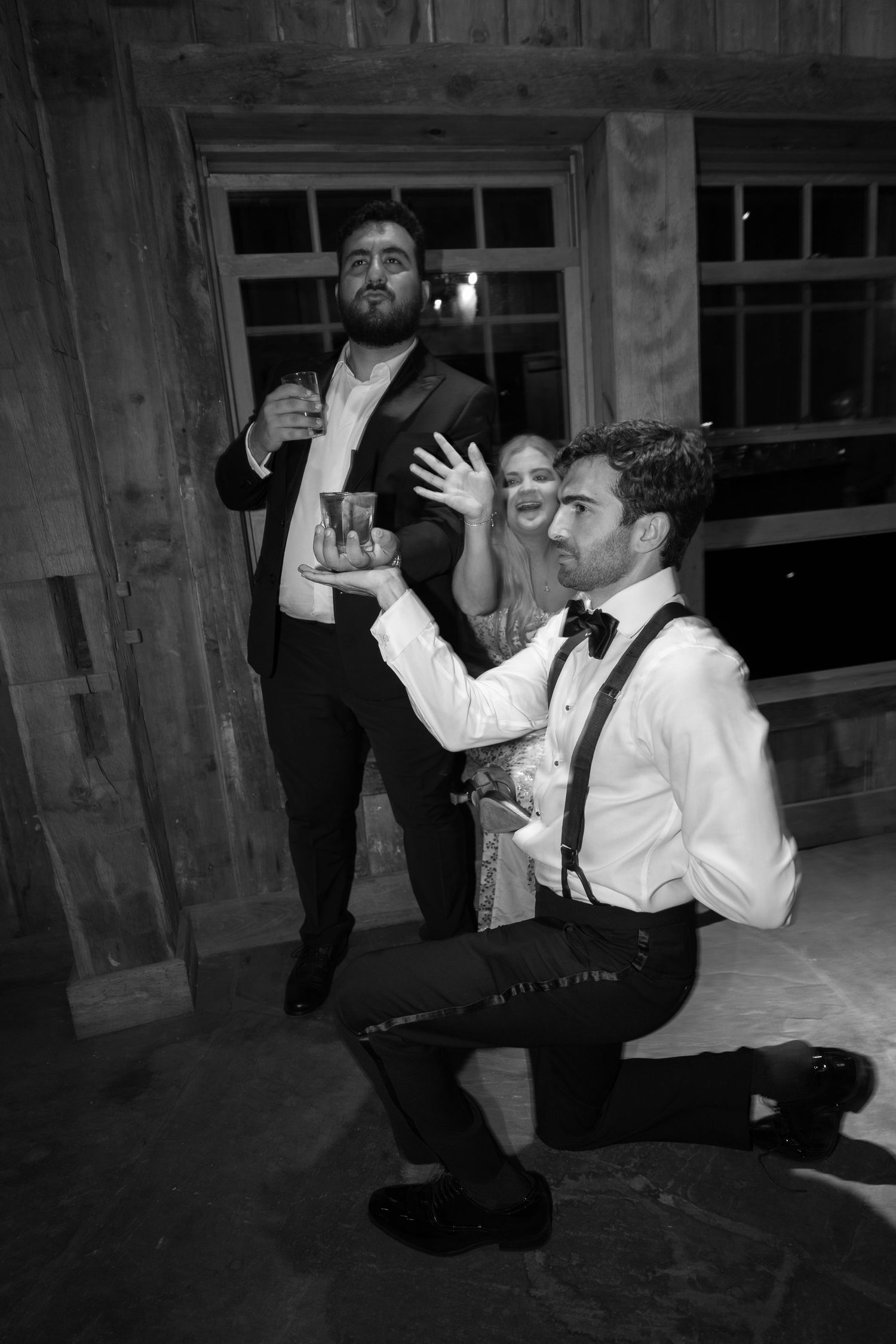 Black and white photo of wedding reception dancing in rustic wooden venue.