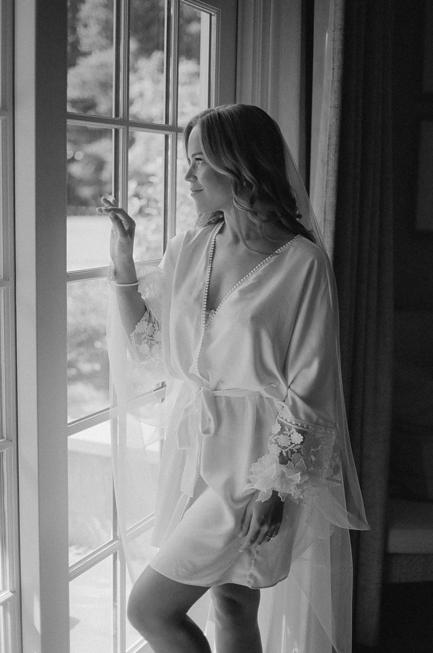 Artistic black and white photography of bridal preparations by window light.