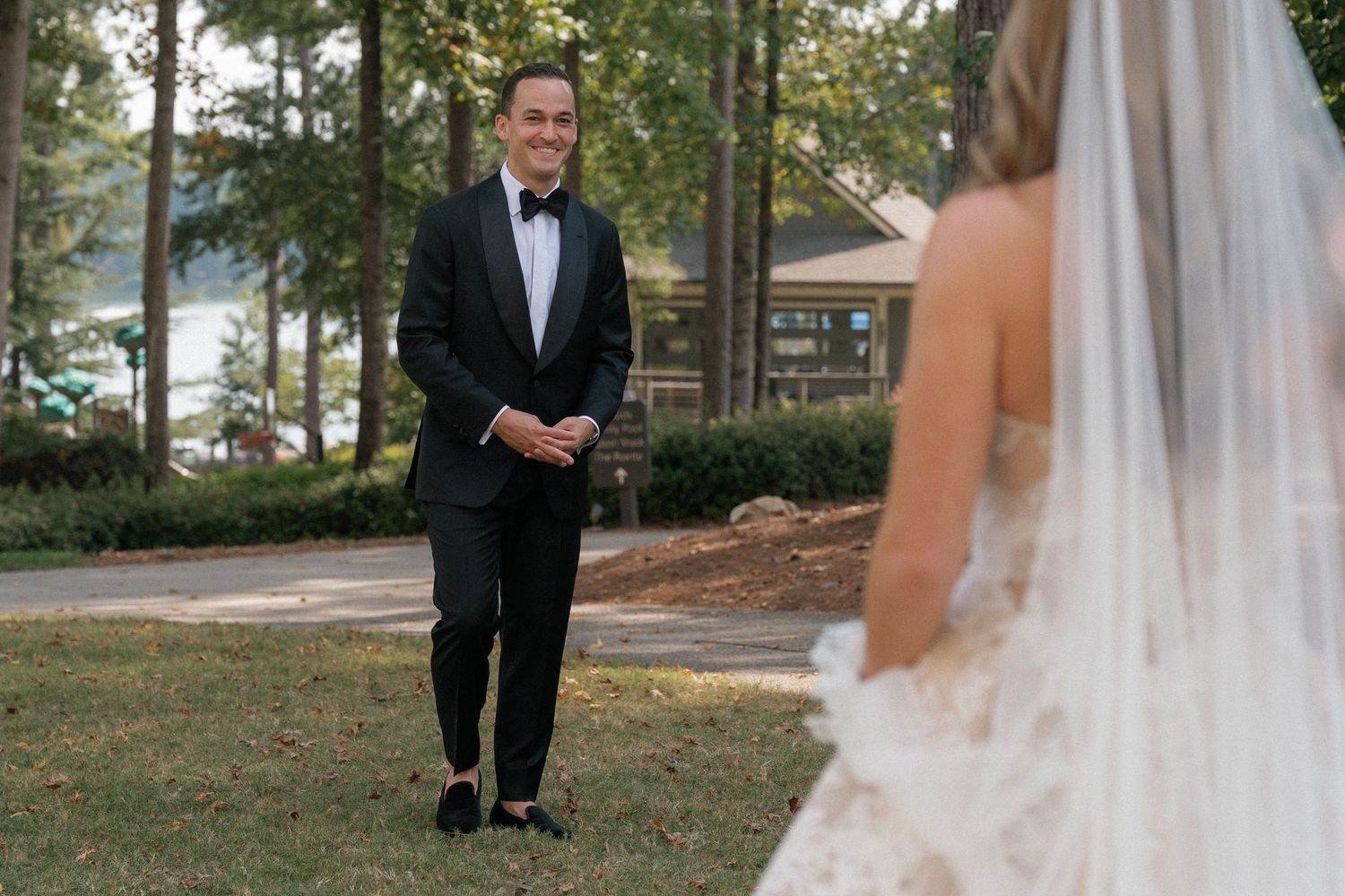 A first look moment captured between a couple at their outdoor wedding near a lake.