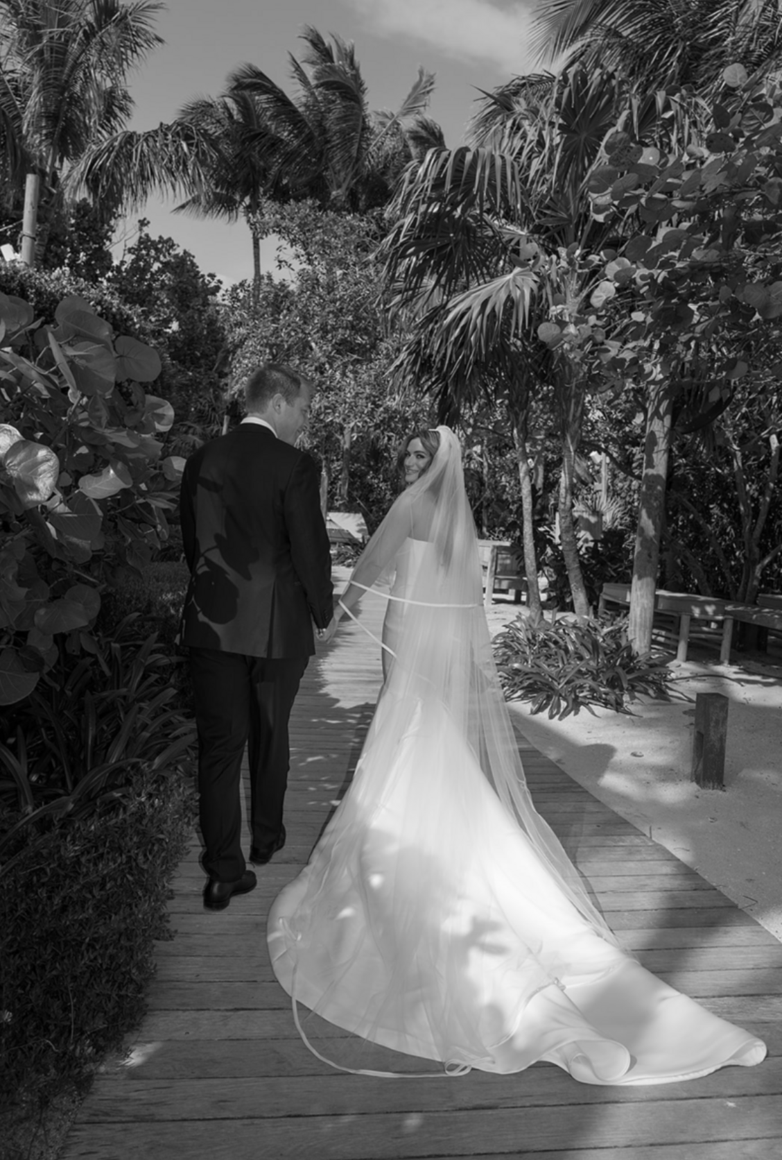 Wedding ceremony on a tropical palm-lined boardwalk in black and white.