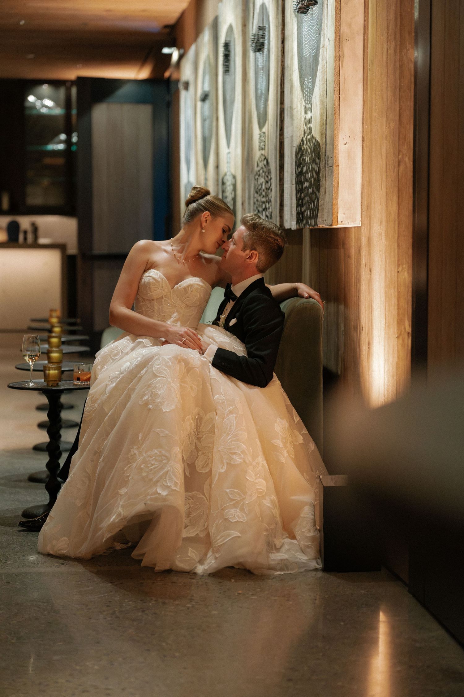A romantic wedding moment captured in a dimly lit hallway with a flowing white gown.