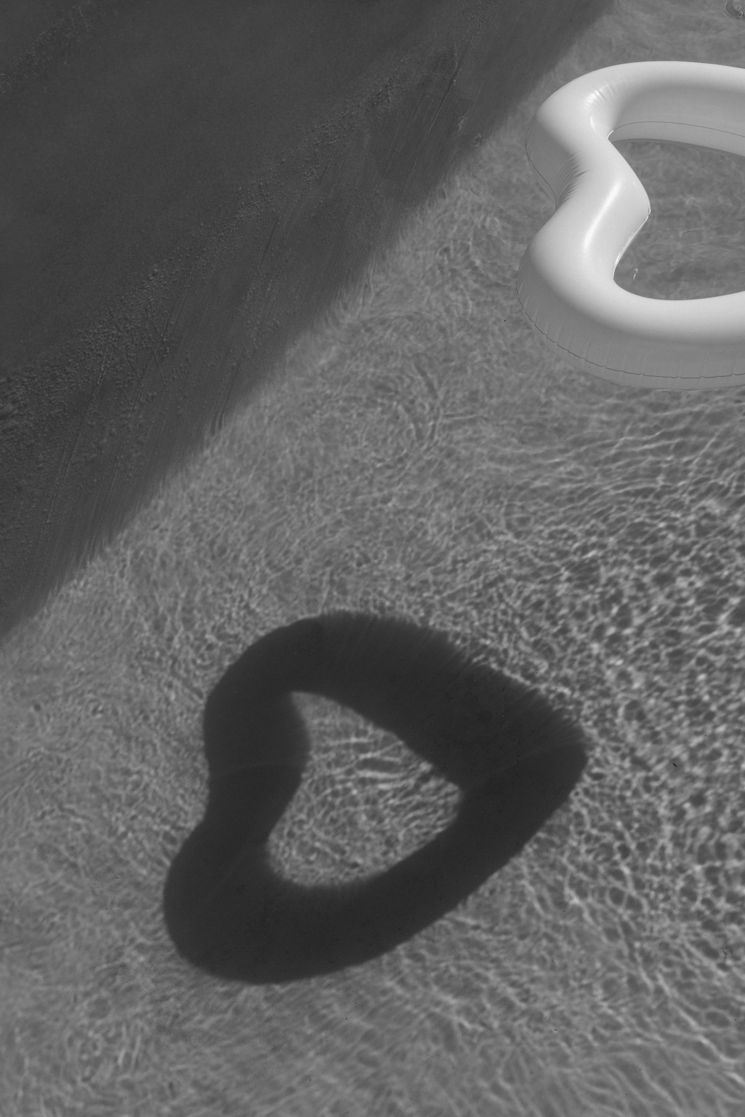 A black and white image showing a heart-shaped shadow on a textured surface.