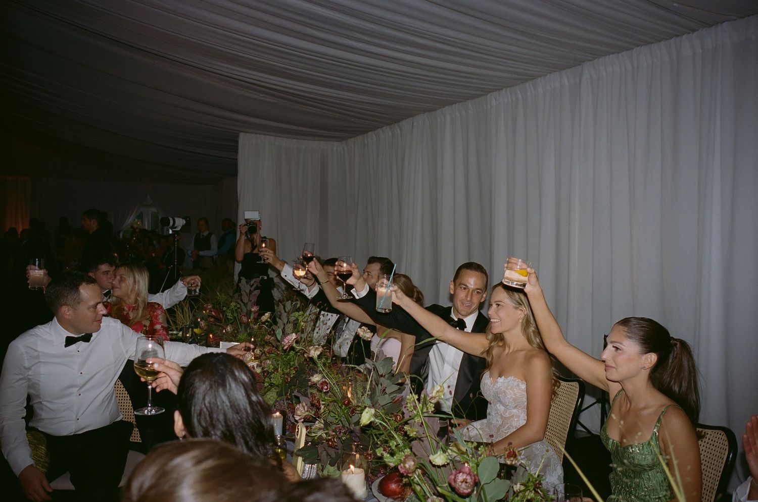Wedding reception celebration with guests dancing under draped white fabric ceiling.