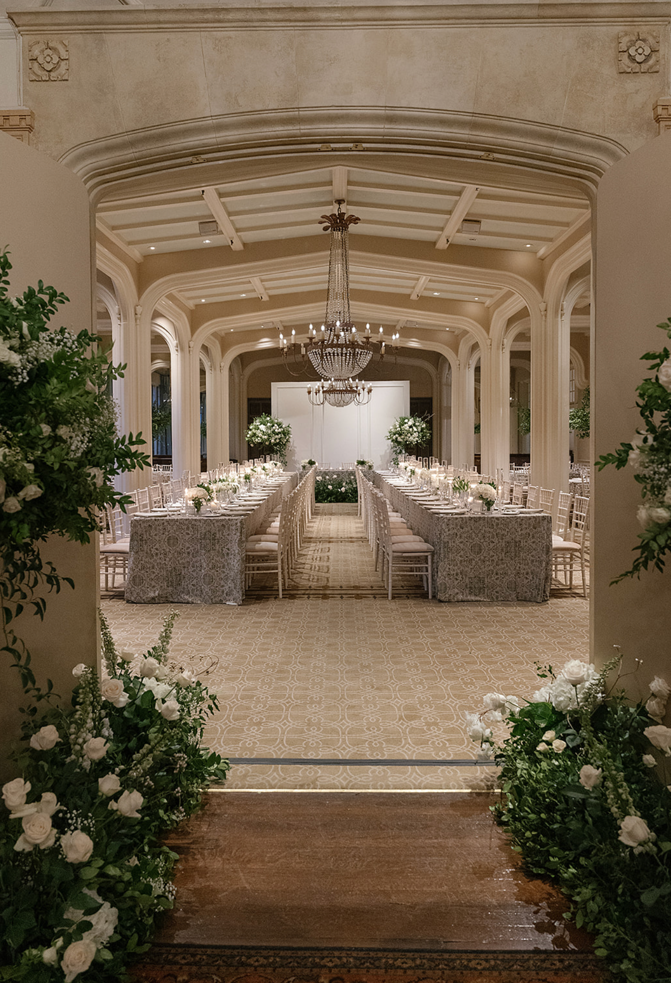 Elegant white wedding reception hall with arched ceilings and floral decorations.