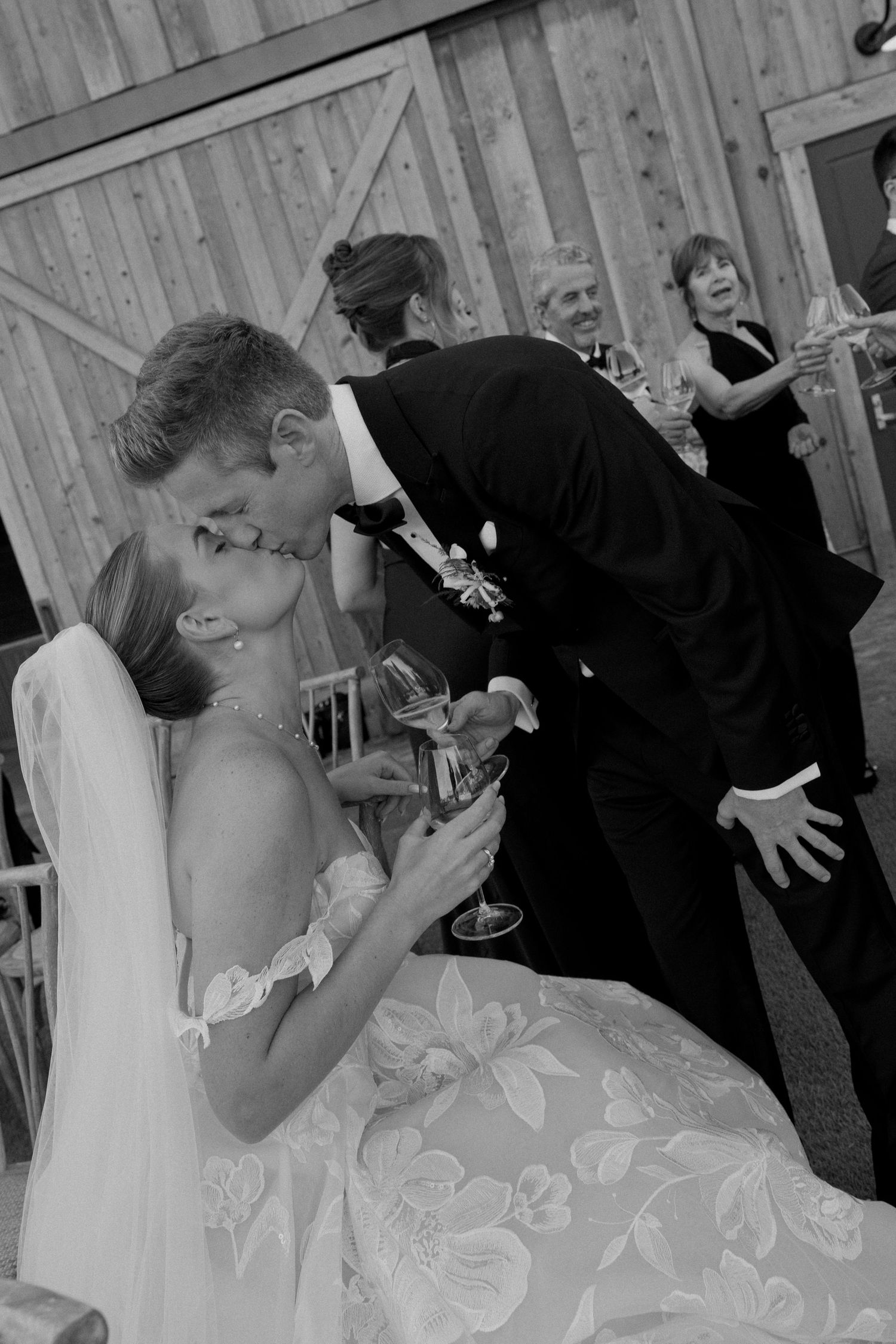 Black and white photo of romantic moment between newlyweds at rustic venue.