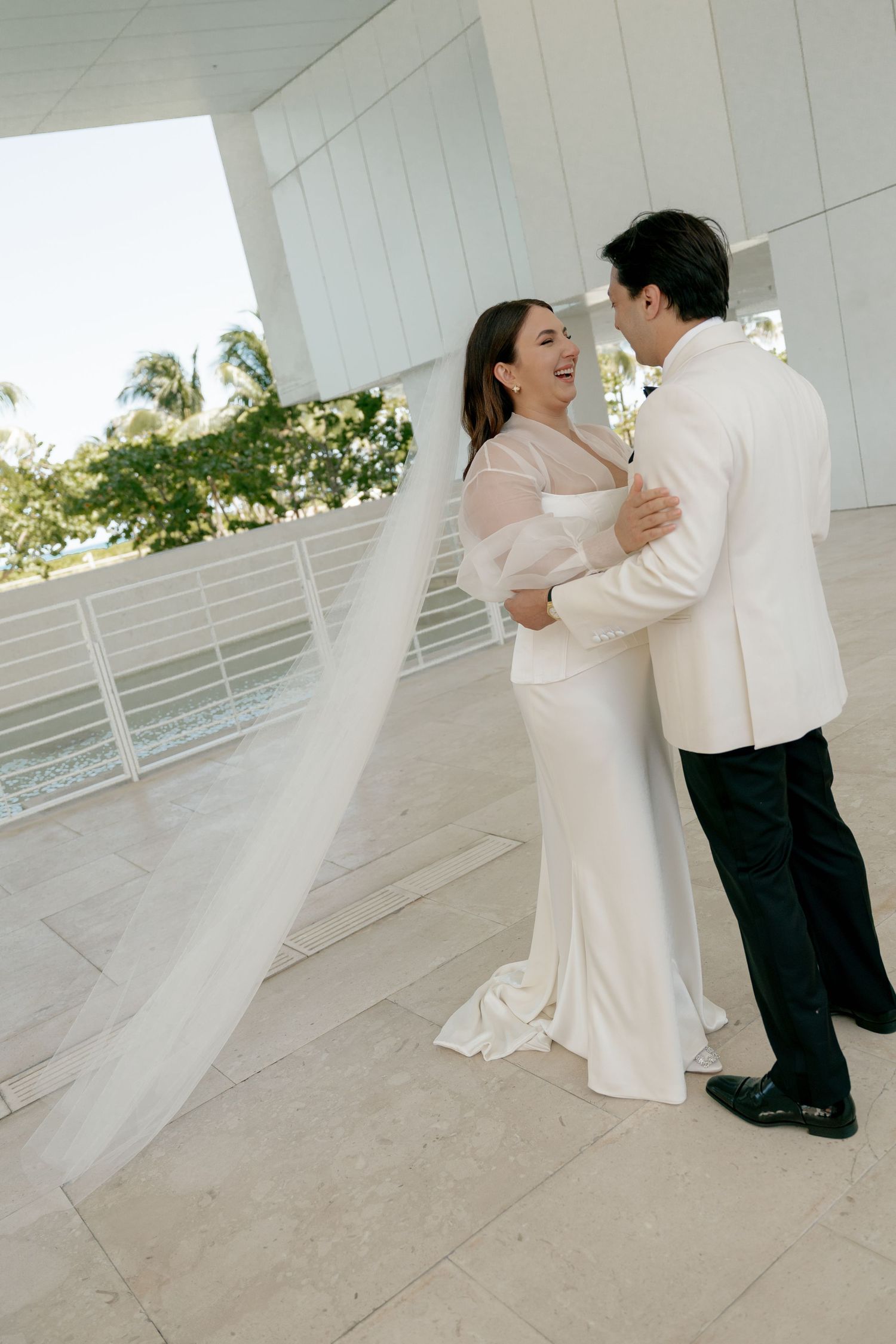 Wedding couple dancing and twirling on an elegant white terrace.