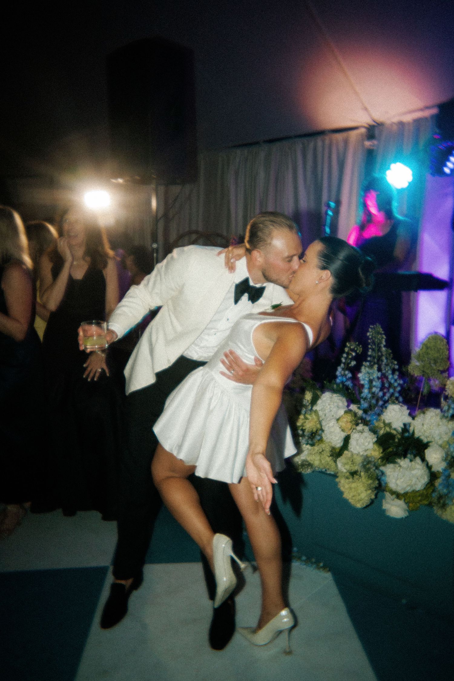 A couple performs a dramatic dance dip move during their wedding reception.
