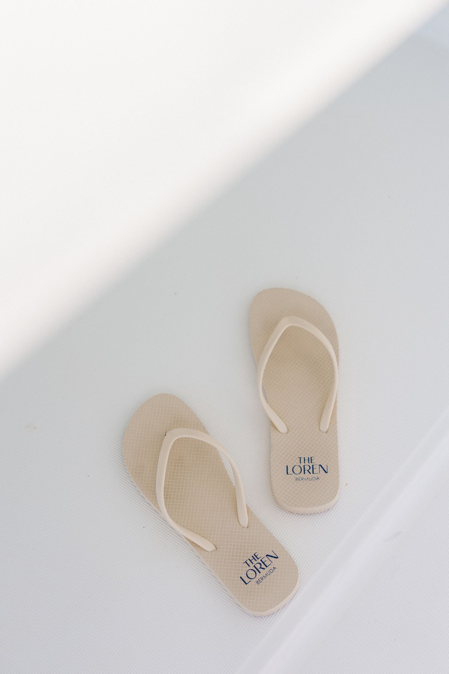 A pair of beige flip-flops or sandals are shown on a plain white background.