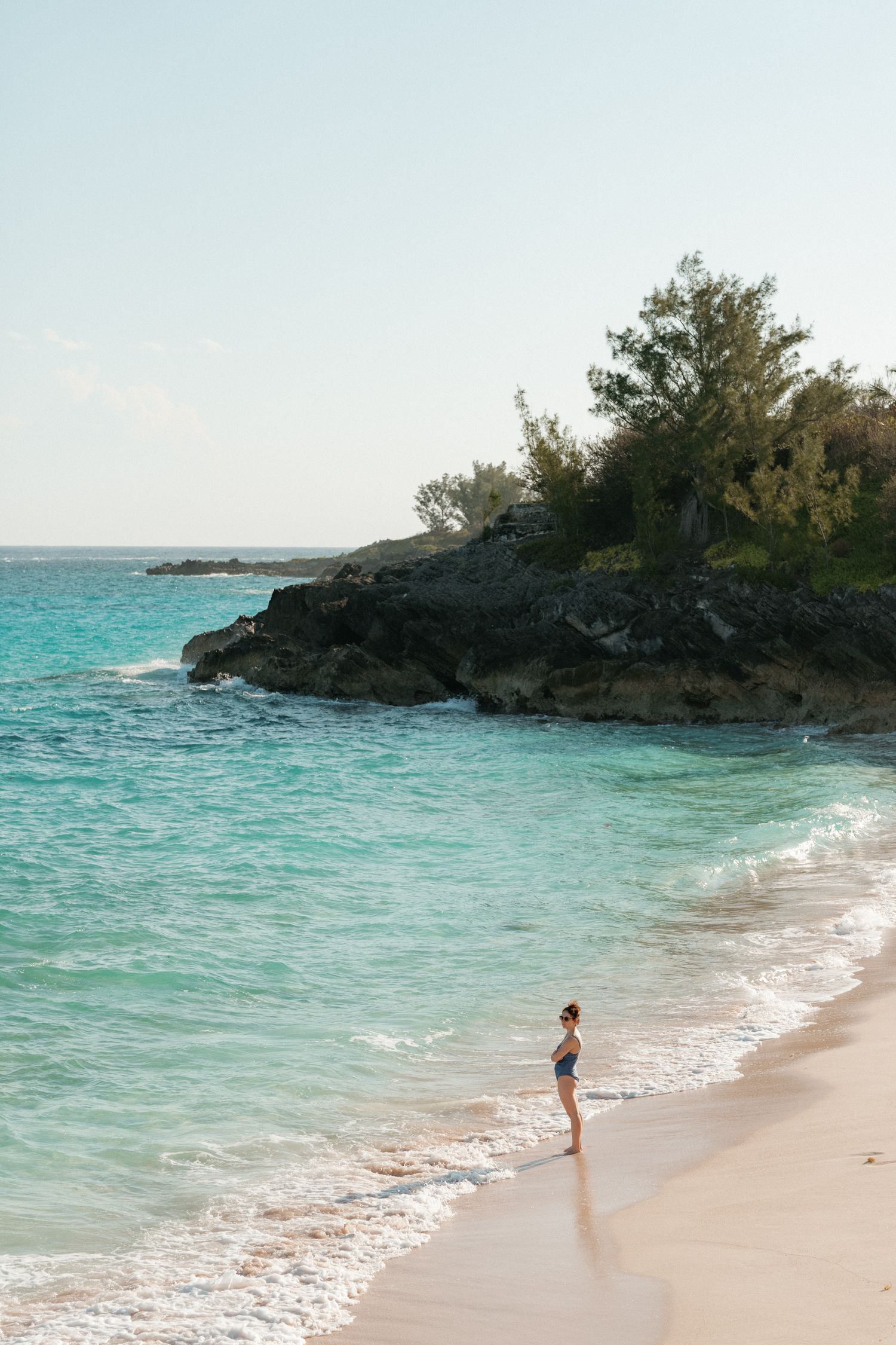 A scenic view of a tropical beach with turquoise water and lush vegetation.