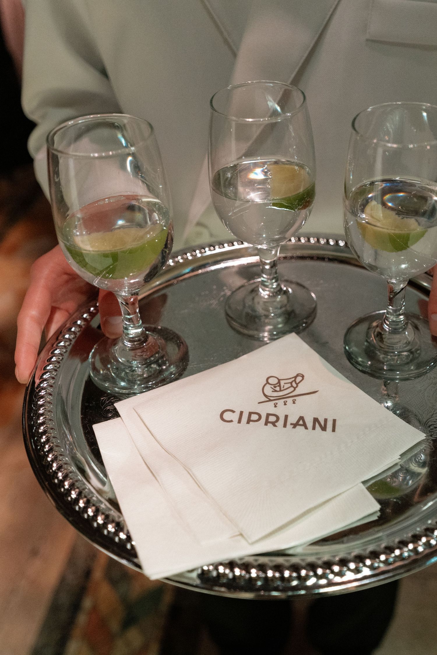 A tray with glasses of wine and a menu with the name 'Cipriani' on it.