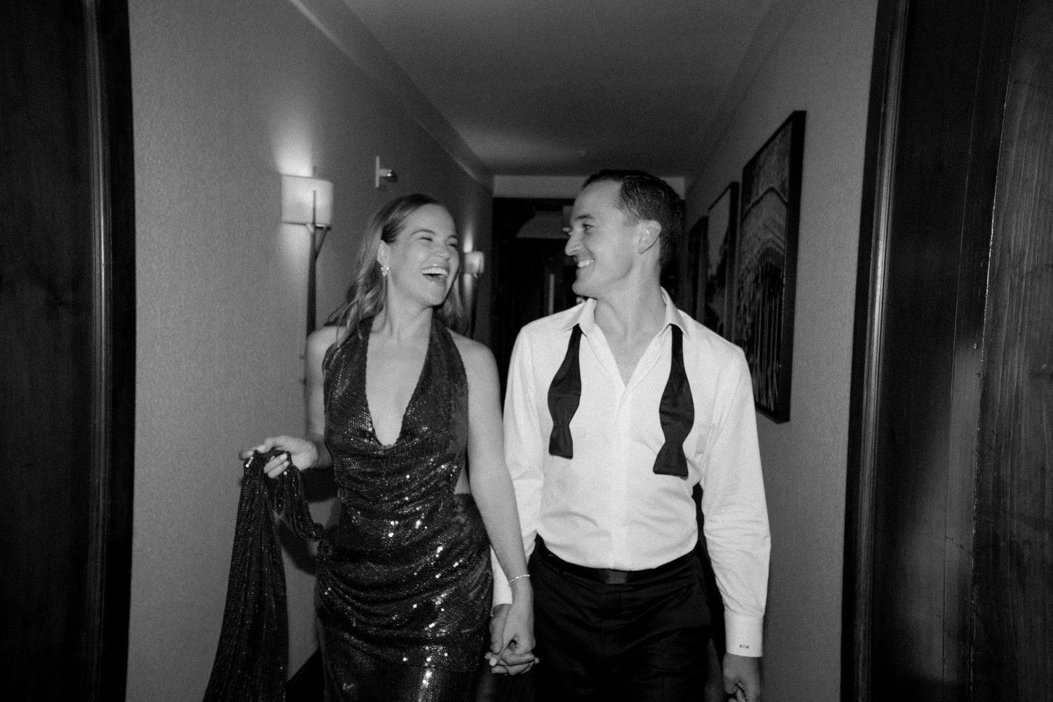 A couple shares a candid moment laughing together in an elegant hallway.