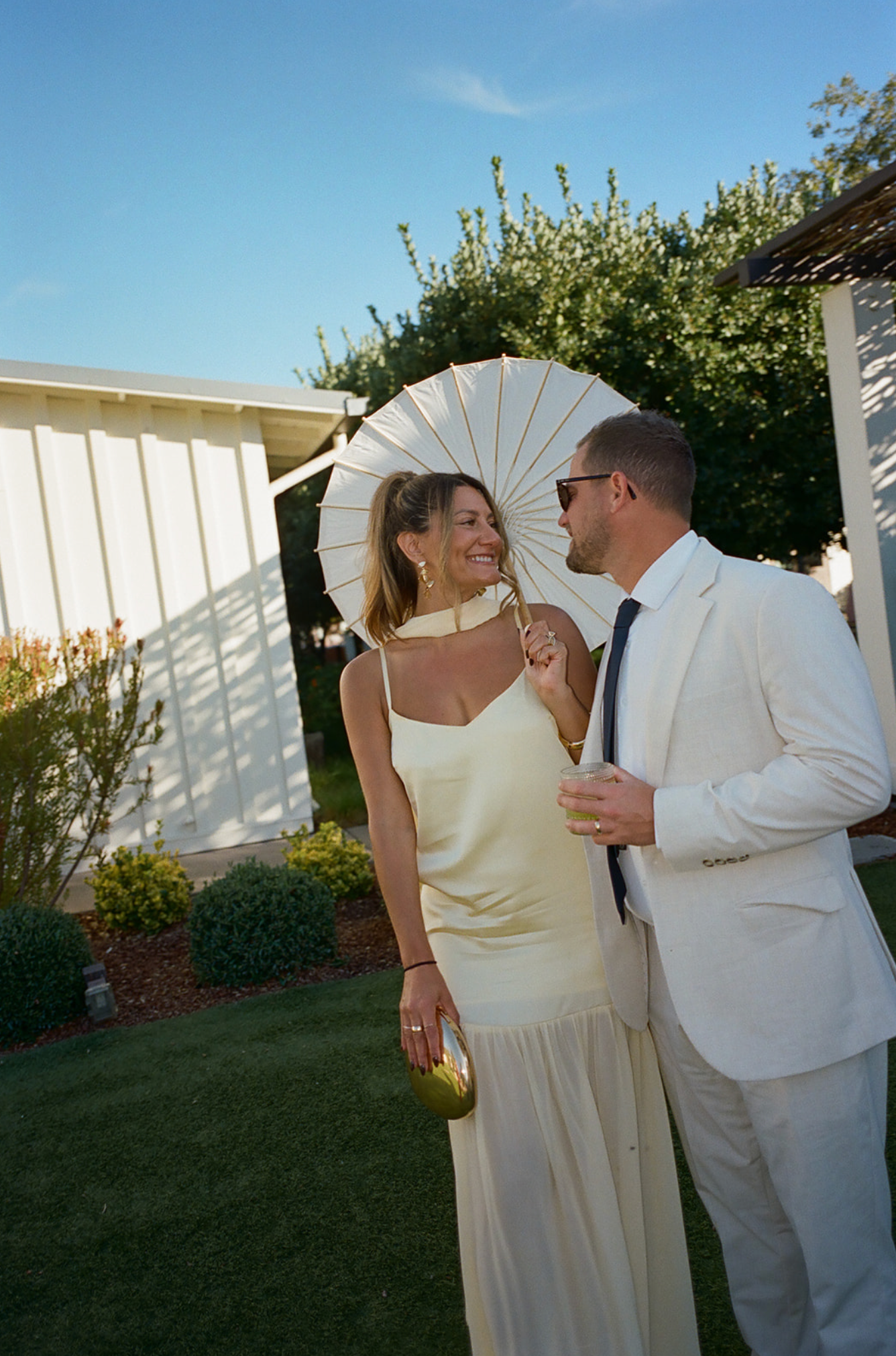Sunny outdoor portrait with a white parasol and elegant summer attire.