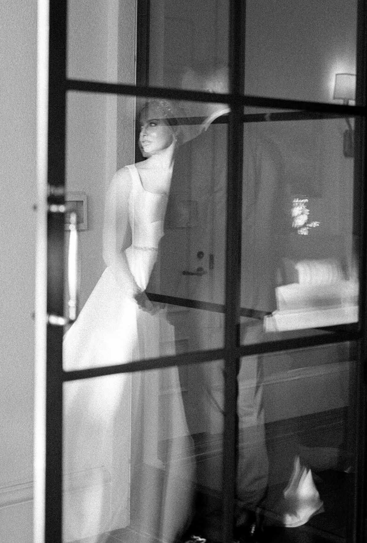 Artistic black and white silhouettes of wedding dresses through window panes.