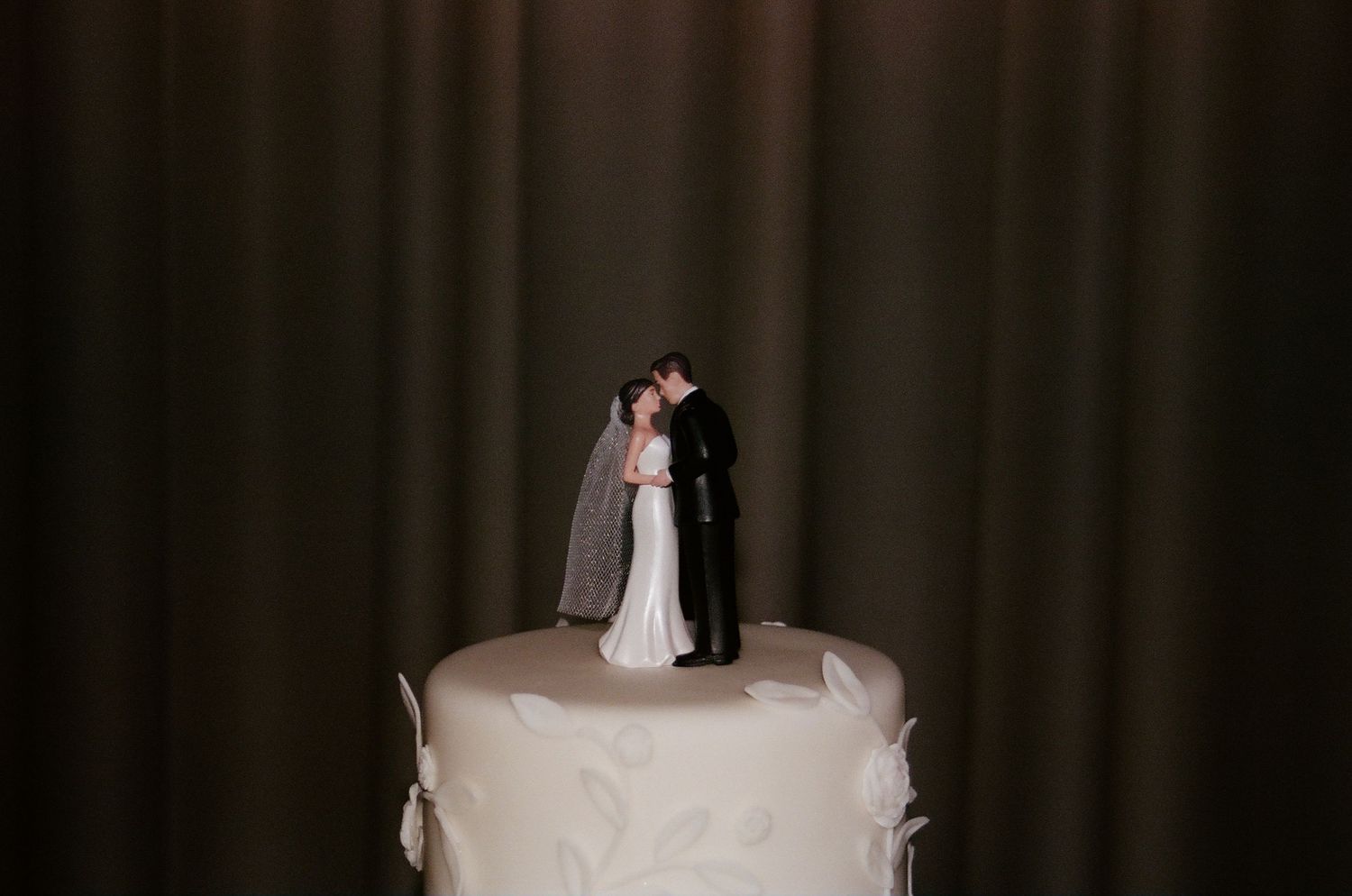 Wedding cake topped with a traditional bride and groom figurine.