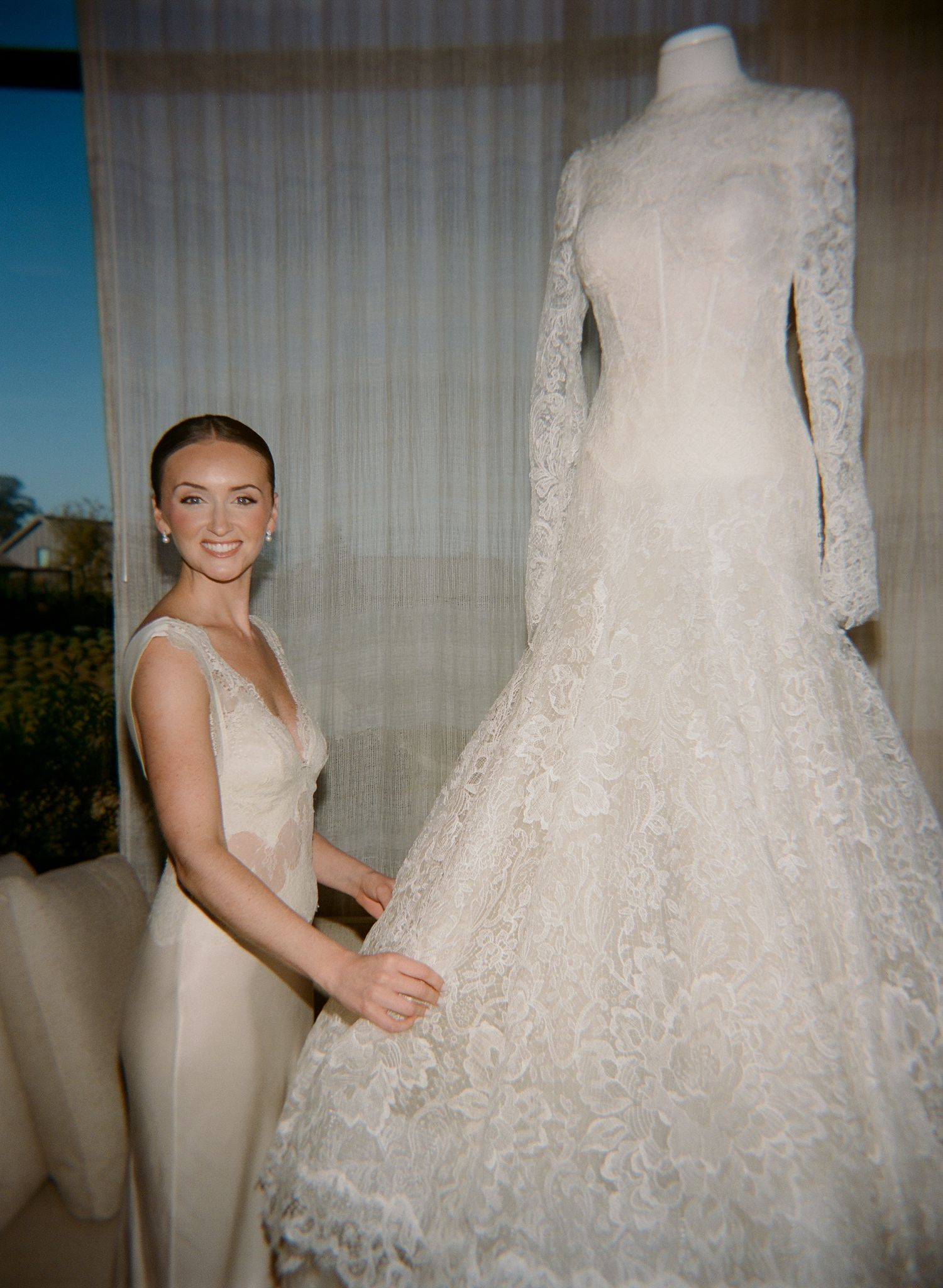 Close-up details of an ornate white lace wedding dress being prepared before the ceremony.