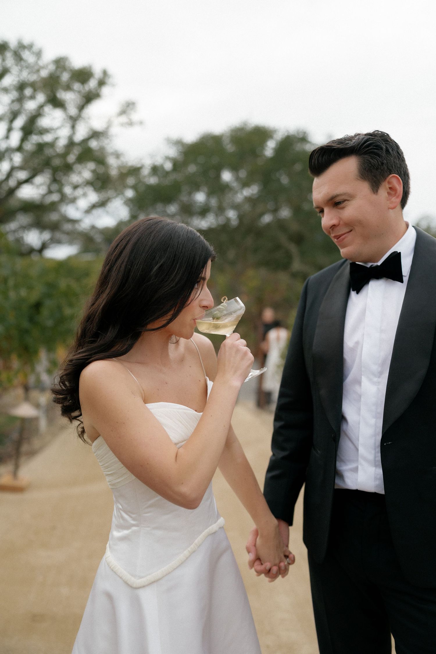 A bride in a white dress shares a tender moment with her groom in formal attire outdoors.