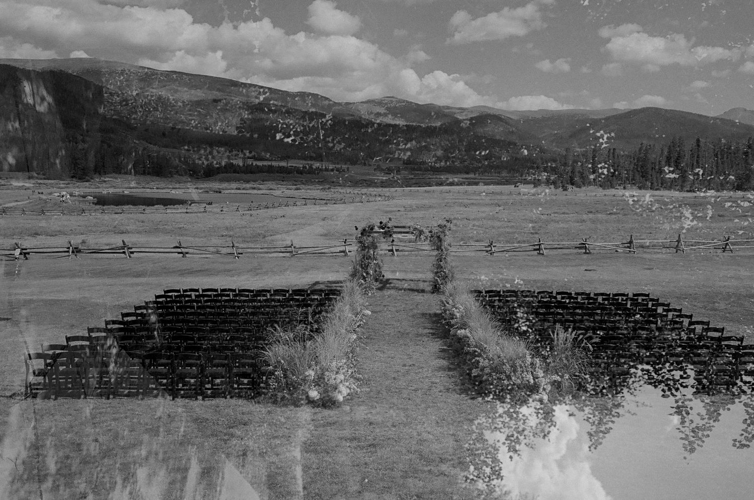 Wide panoramic view of a mountain landscape with wooden fences and seating arrangements.