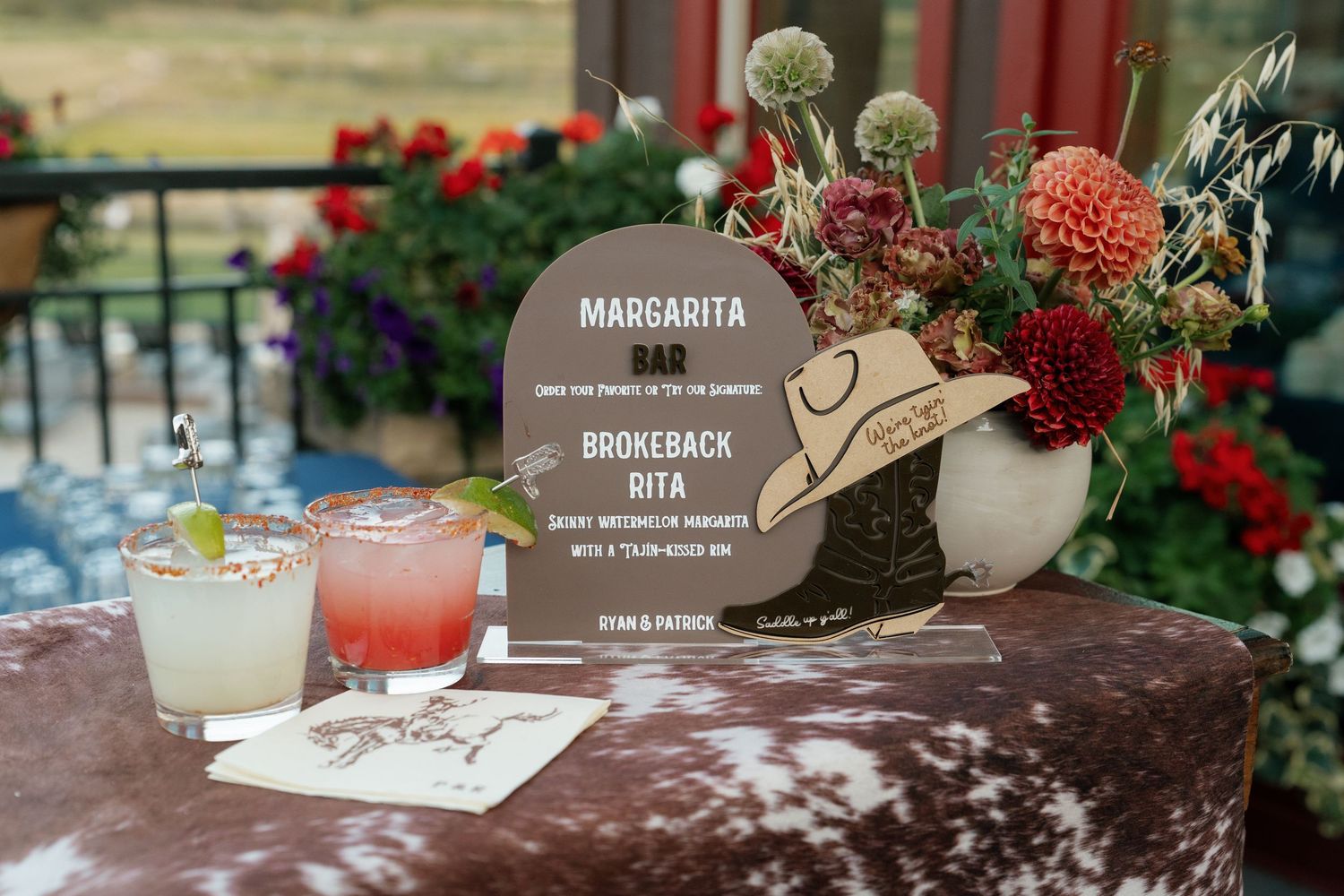 Cocktail menu and drinks display with floral decorations on rustic table.