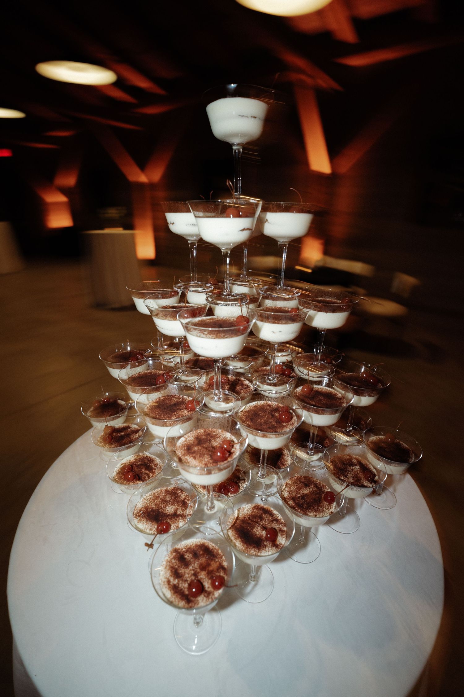 Pyramid display of champagne glasses on a white tablecloth at an event.