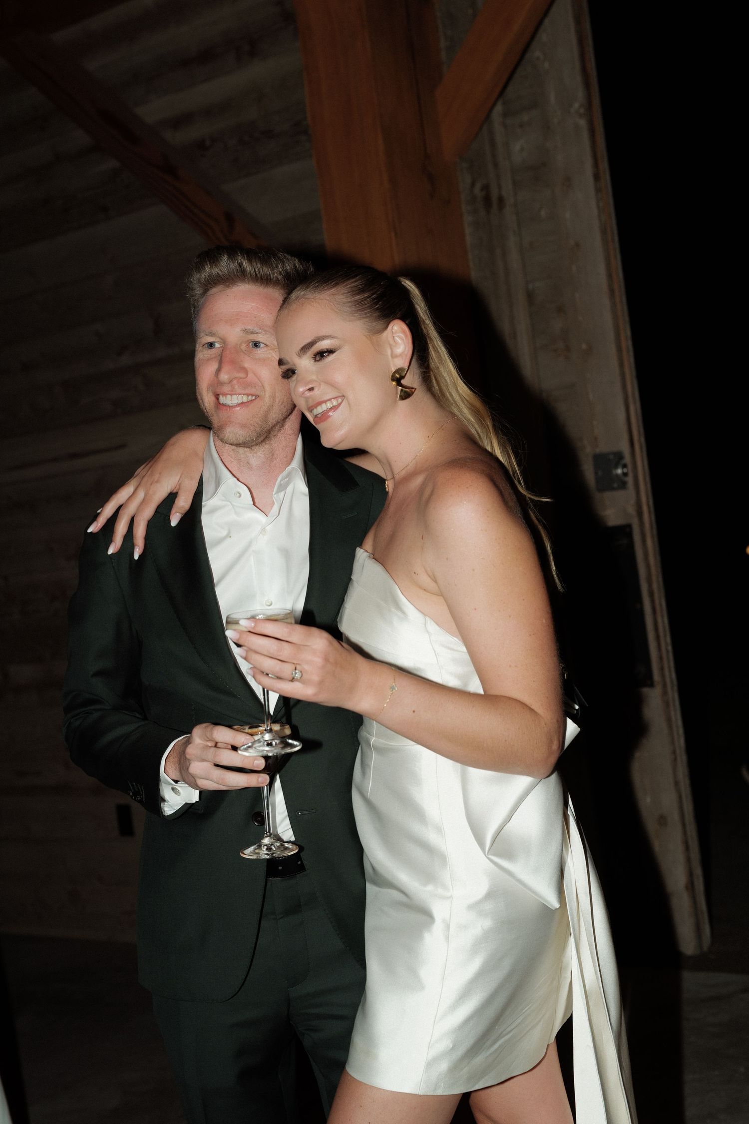 A couple shares a joyful moment while holding champagne glasses at an evening celebration.