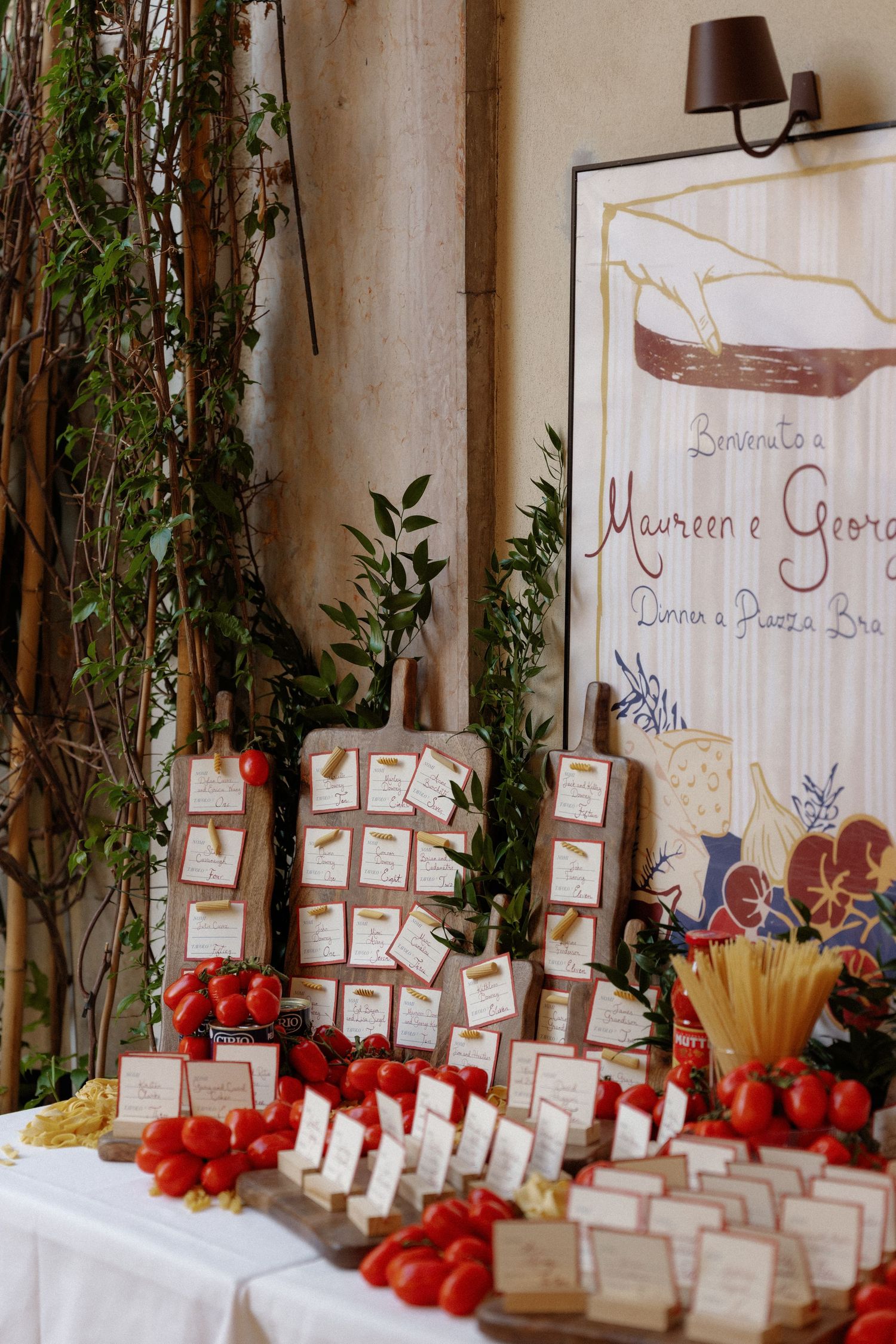 Elegant Italian wedding escort card table with fresh tomatoes, cutting boards, and a decorative welcome sign for Maureen and George.