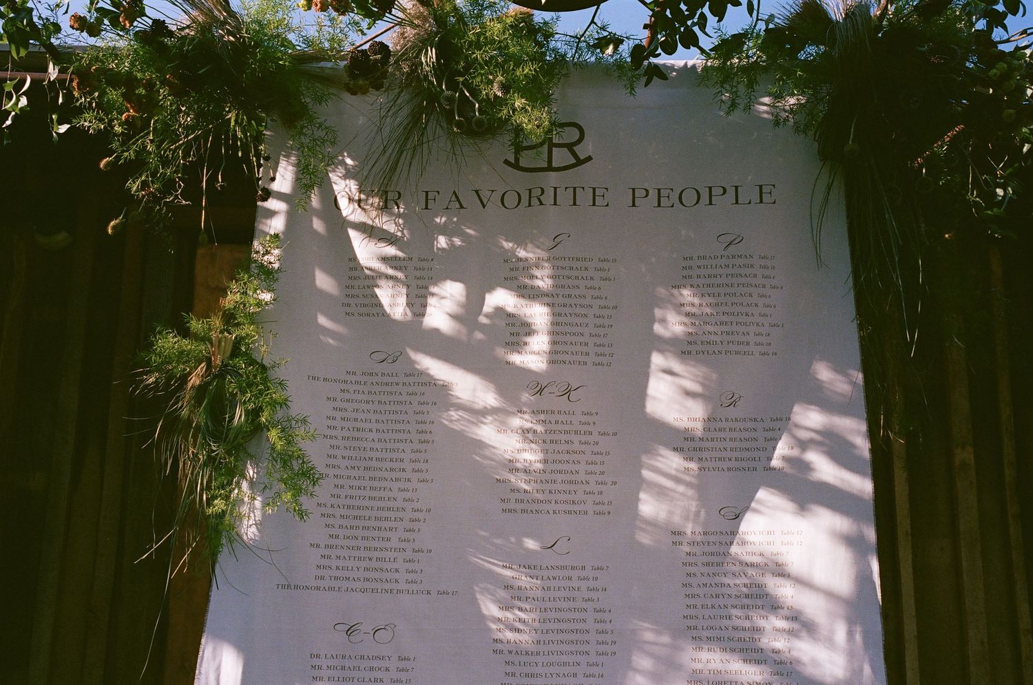 Wedding program or menu displayed under dappled sunlight and tree shadows.