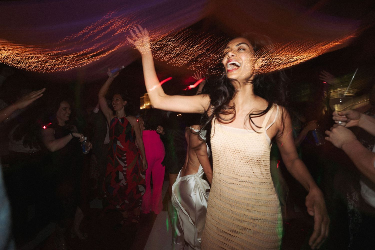 People dancing and celebrating at a lively nighttime party with dynamic lighting and movement.