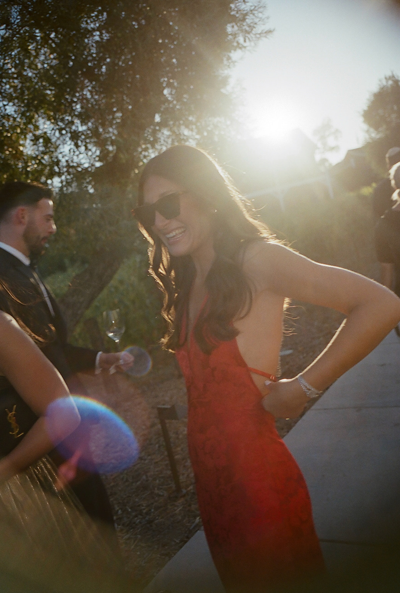 Wedding celebration during golden hour with dancing silhouettes in sunlit outdoor setting.