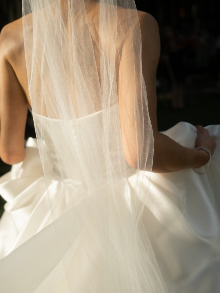 Close-up detail of a white wedding dress showing delicate tulle veil and structured bodice.