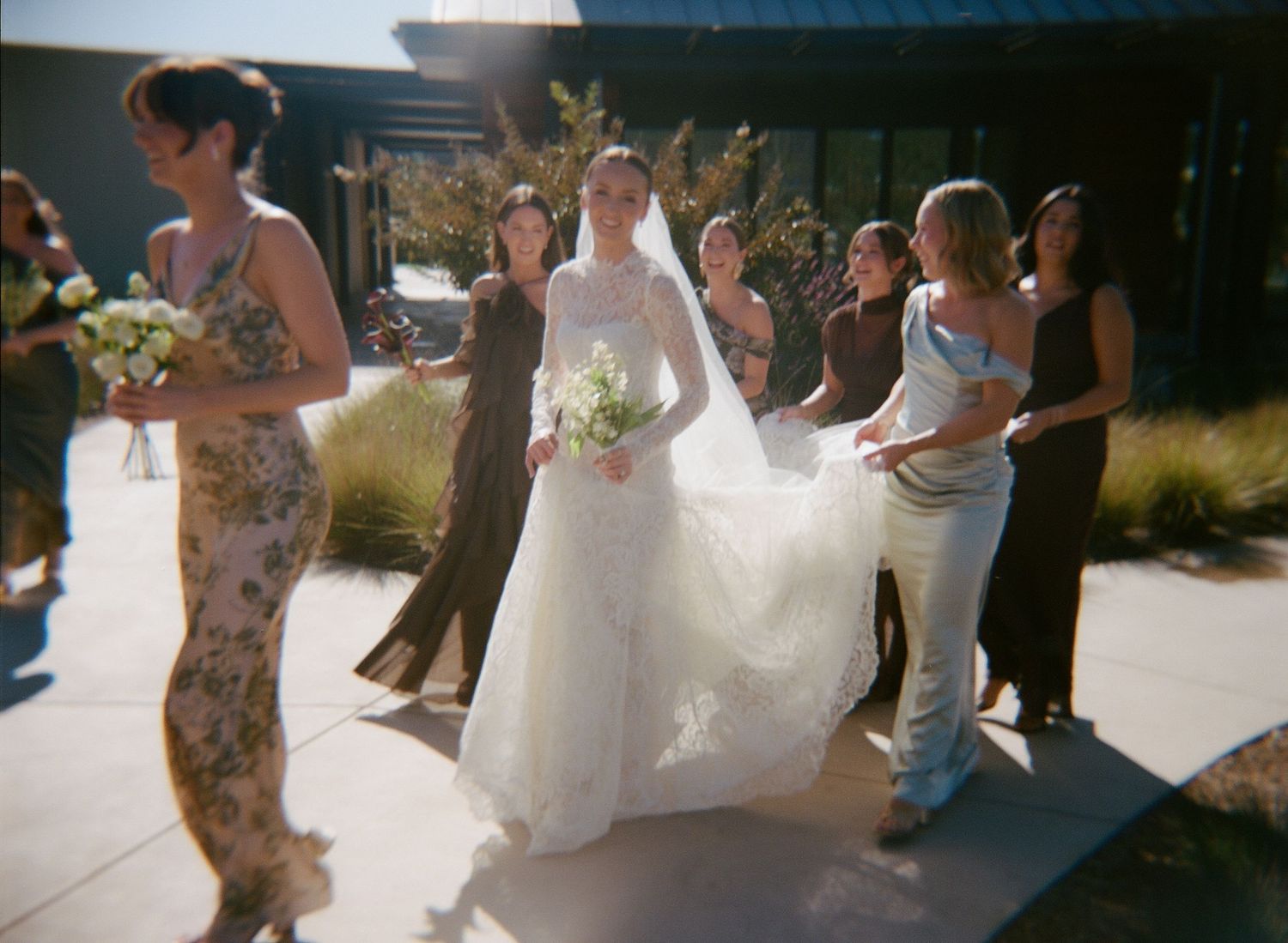 Wedding party dances and celebrates outdoors in natural lighting.