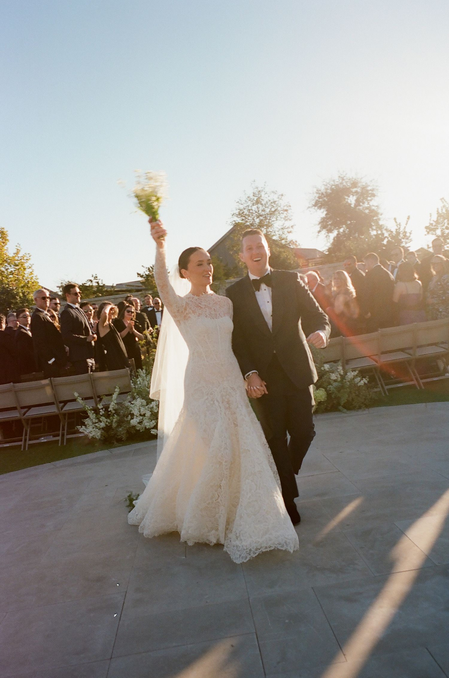 Celebratory moment during outdoor wedding ceremony with white floral decorations.