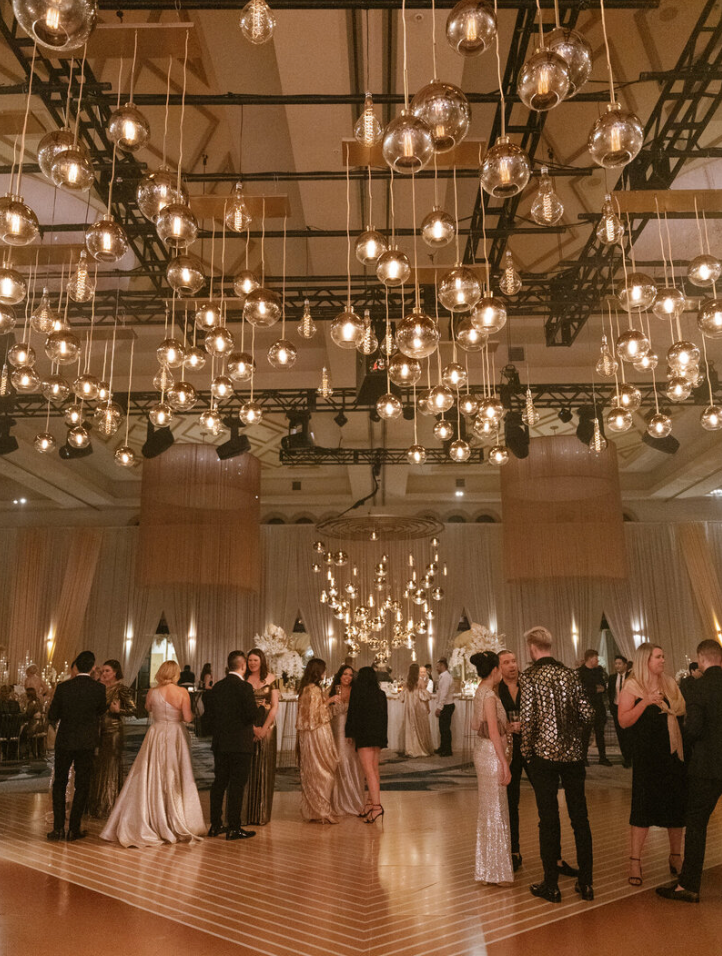 Wedding reception dance floor under stunning glass globe chandelier lighting installation.
