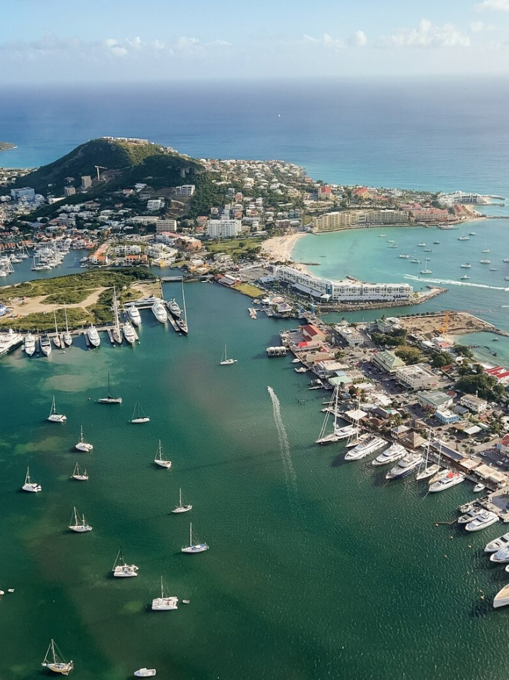 Aerial view of a coastal marina with boats and yachts docked in turquoise waters.