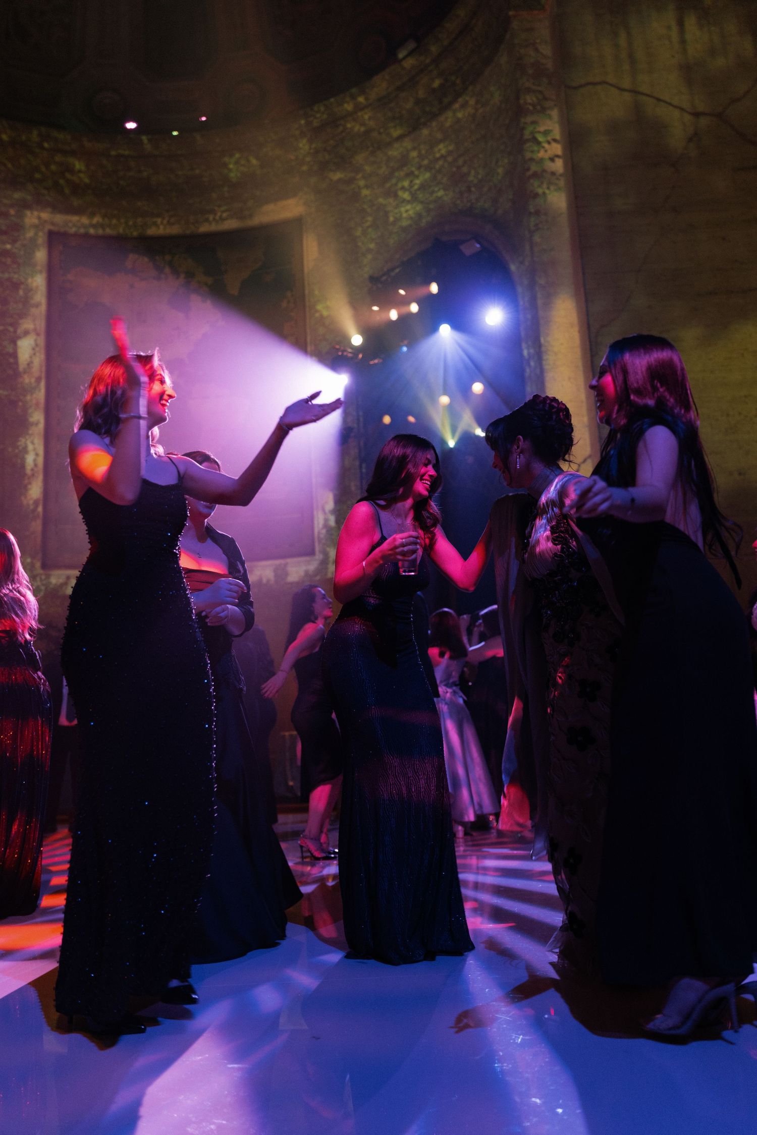 A woman in a black dress performing on a stage in a dimly lit room.