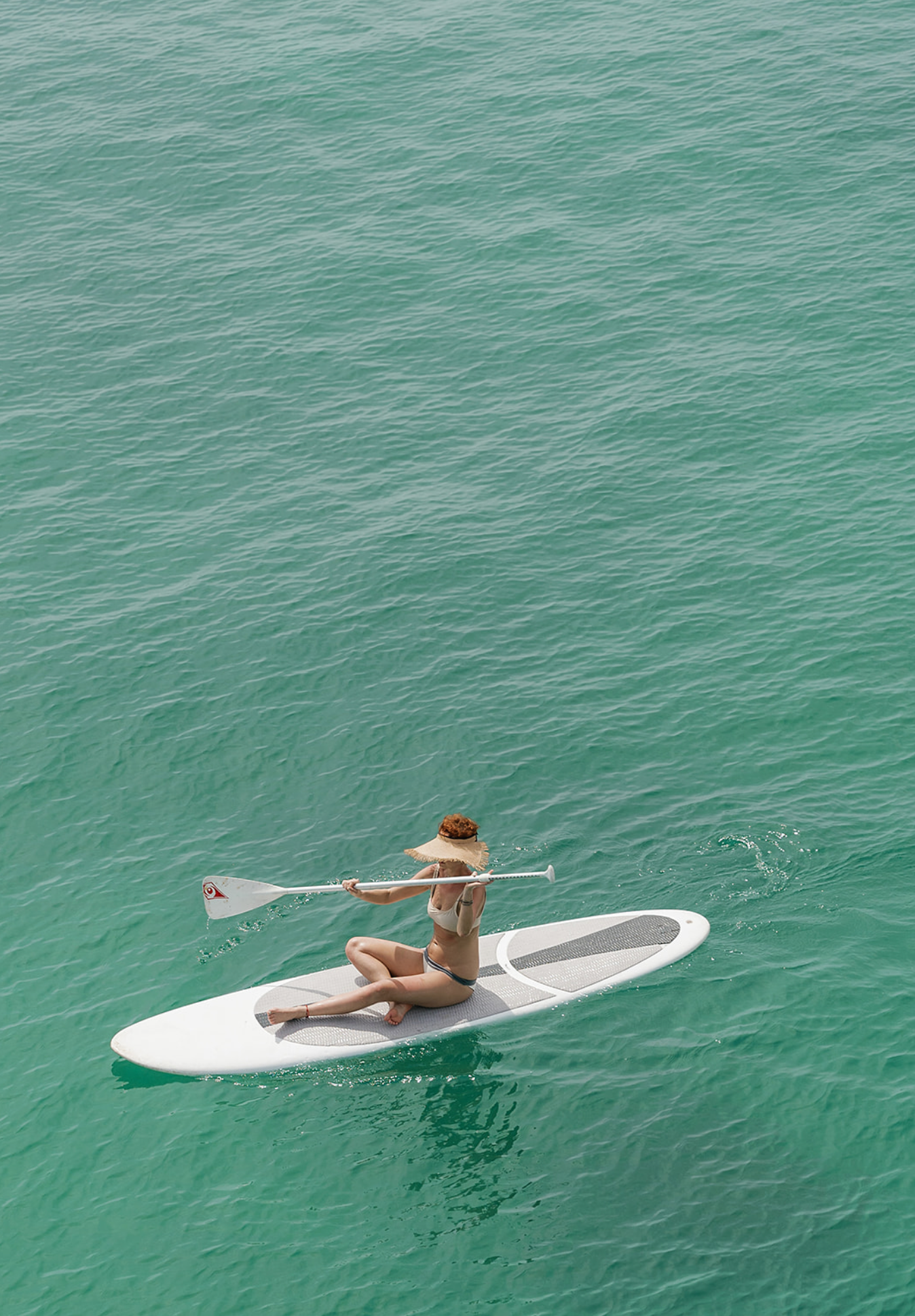 A sequence showing a paddleboarder gliding across turquoise waters on a calm sunny day.