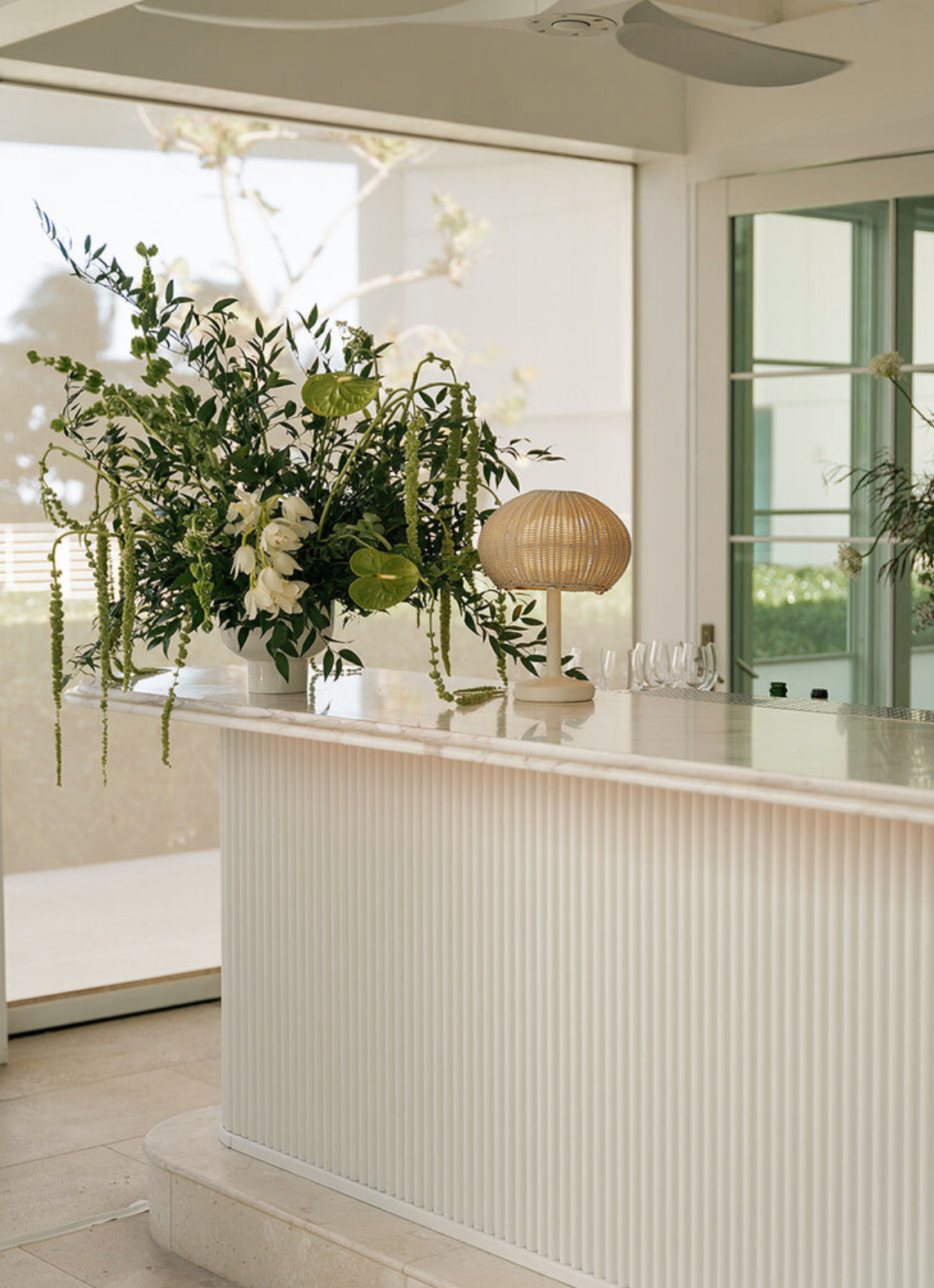Modern white wedding venue interior with natural greenery and minimalist design elements.